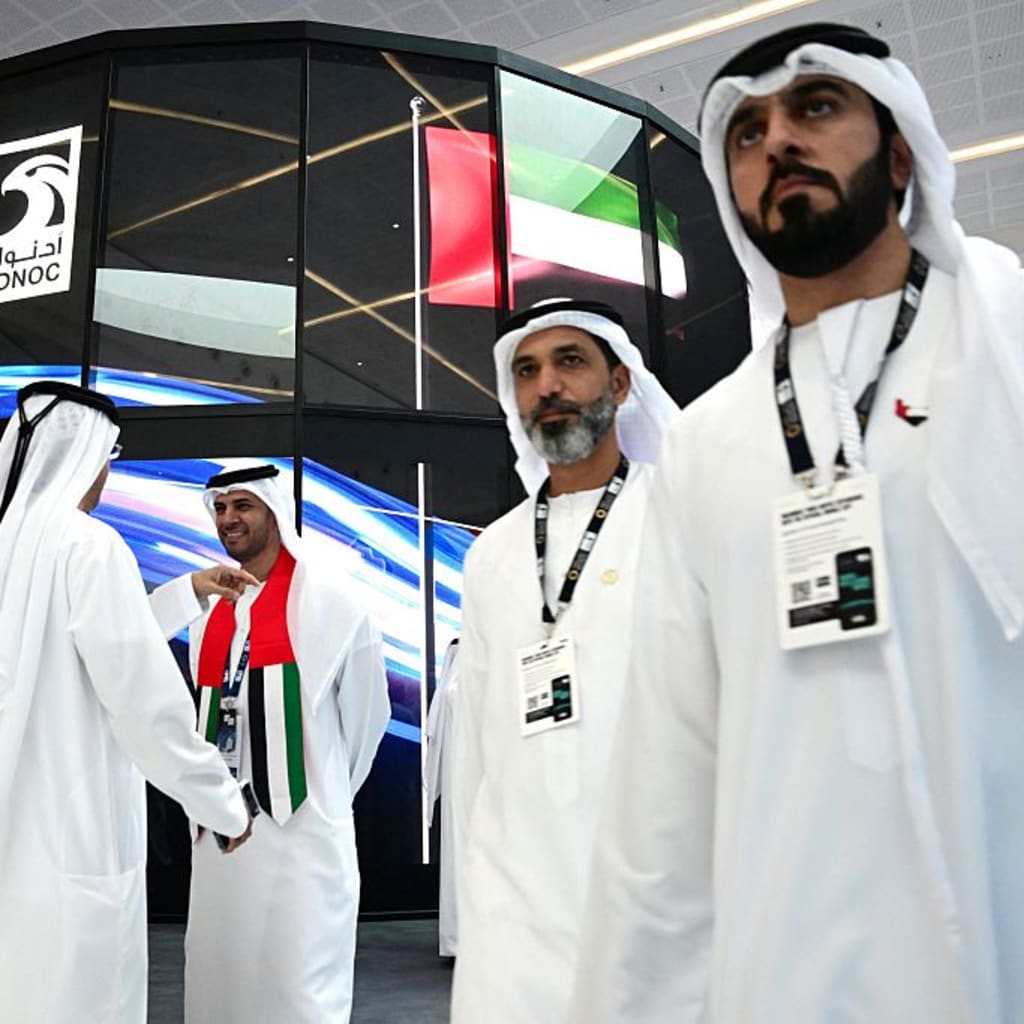 Guests stand at the booth of the Abu Dhabi National Oil Company (ADNOC), during the Abu Dhabi International Petroleum Exhibition & Conference (ADIPEC) in Abu Dhabi on November 3, 2025.