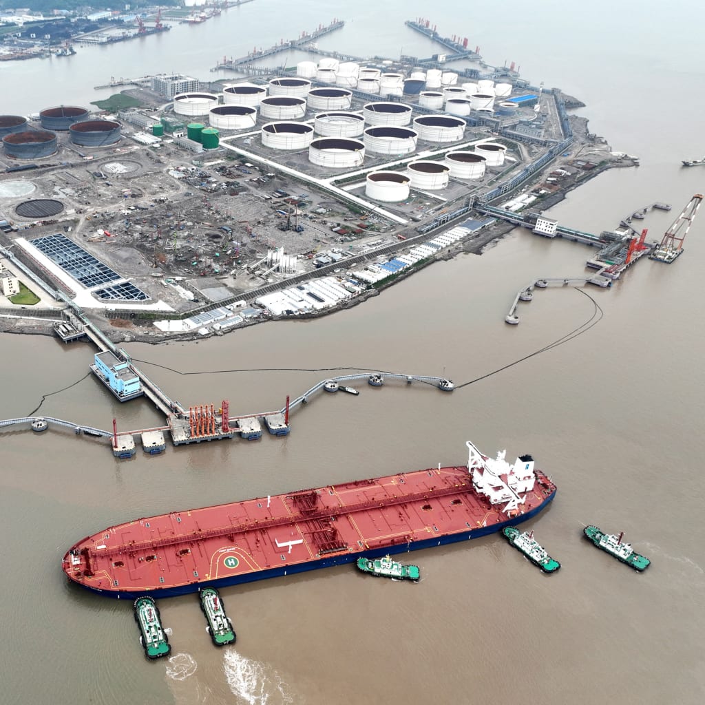 An aerial view shows tugboats helping a crude oil tanker to berth at an oil terminal, off Waidiao Island in Zhoushan, Zhejiang province, China July 18, 2022. cnsphoto via REUTERS
