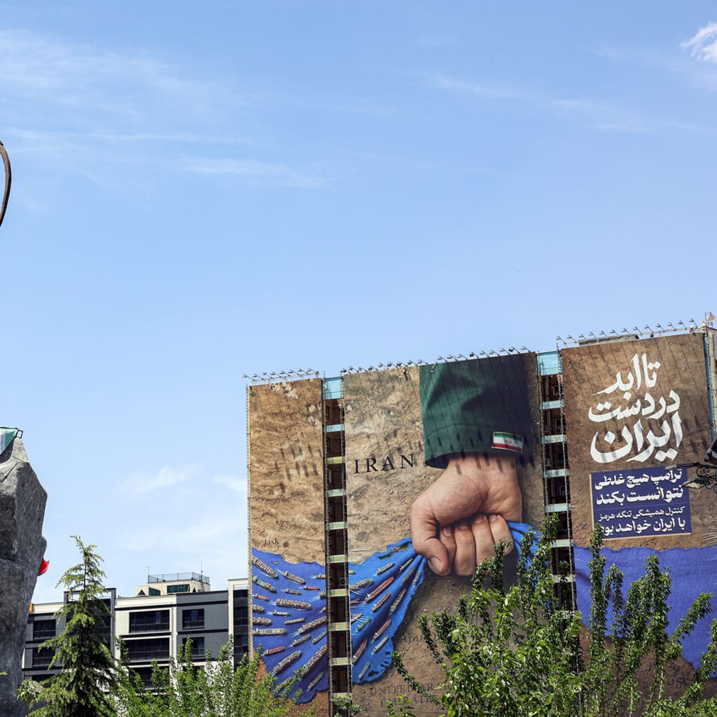 A statue depicting Persian mythical figure Arash the Archer, who according to tradition defined the border area between Persia and the Turanians, is displayed near a billboard on the facade of a building depicting the Strait of Hormuz with a caption in Persian reading "Forever in Iran's Hand", at Vanak Square in Tehran on May 6, 2026.