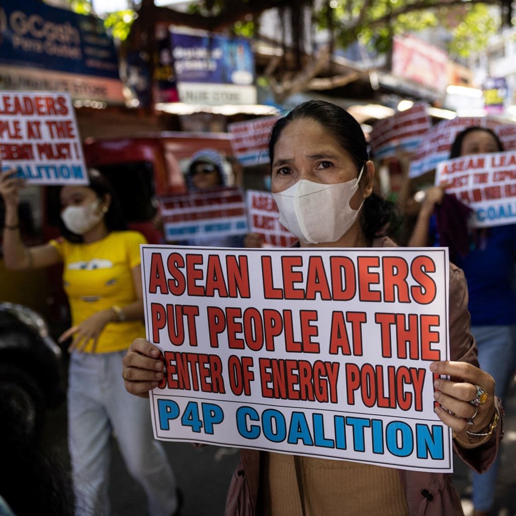 A woman holds up a protest sign reading "ASEAN leaders put people at the center of energy policy P4P coalition".