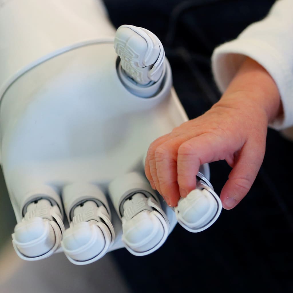 A robot holds the hand of a baby.