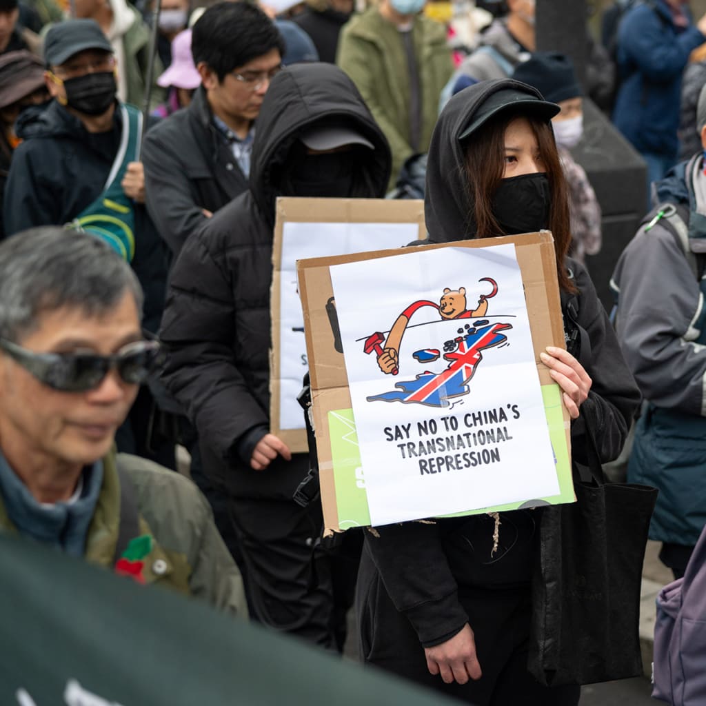 A protester holds a placard saying "Say no to China's transnational repression" during a demonstration.