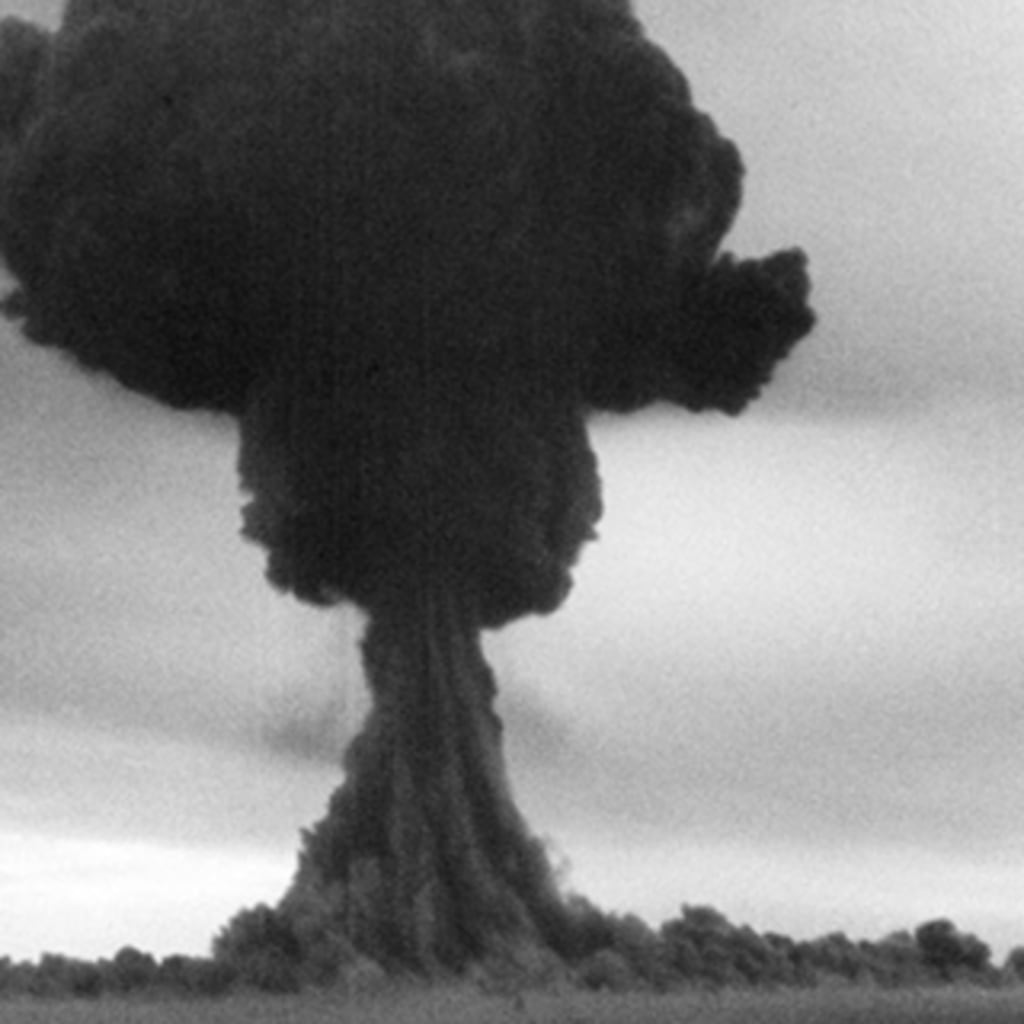 A black and white photograph of a large, black mushroom cloud.