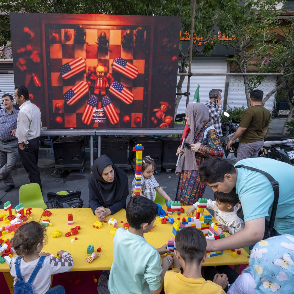 Iranian children play as an animation featuring an effigy of U.S. President Donald Trump and coffins of American soldiers is displayed during a state-run religious rally in downtown Tehran, Iran, on April 29, 2026.