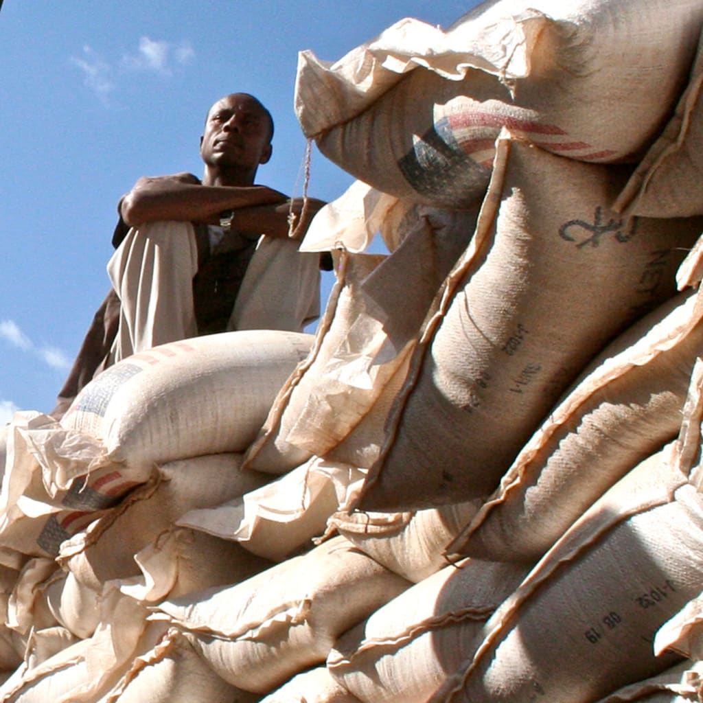 An unidentified government official sits on sacks of wheat donated by the U.S. at a food distribution point near Jijiga, eastern Ethiopia.