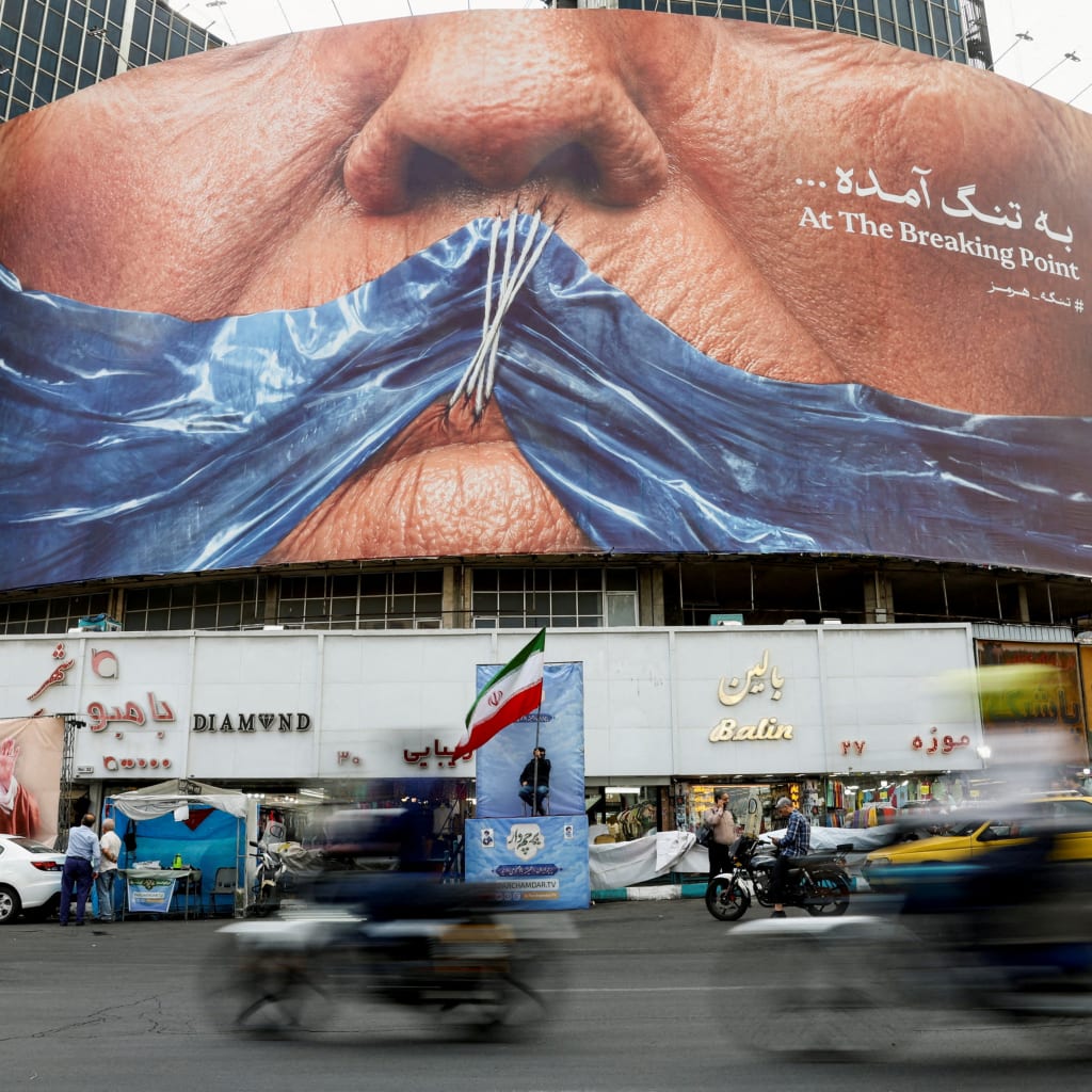 People drive past an anti-U.S. billboard depicting U.S. President Donald Trump and the Strait of Hormuz, in Tehran, Iran, on May 17, 2026.
