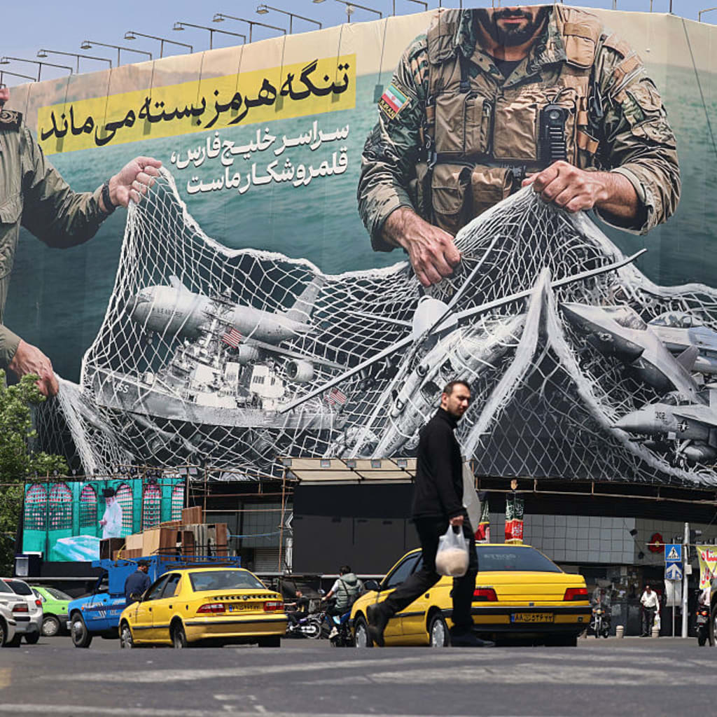 Vehicles drive past a giant billboard reading 'The Strait of Hormuz remains closed' at the Revolution Square in Tehran on April 28, 2026.