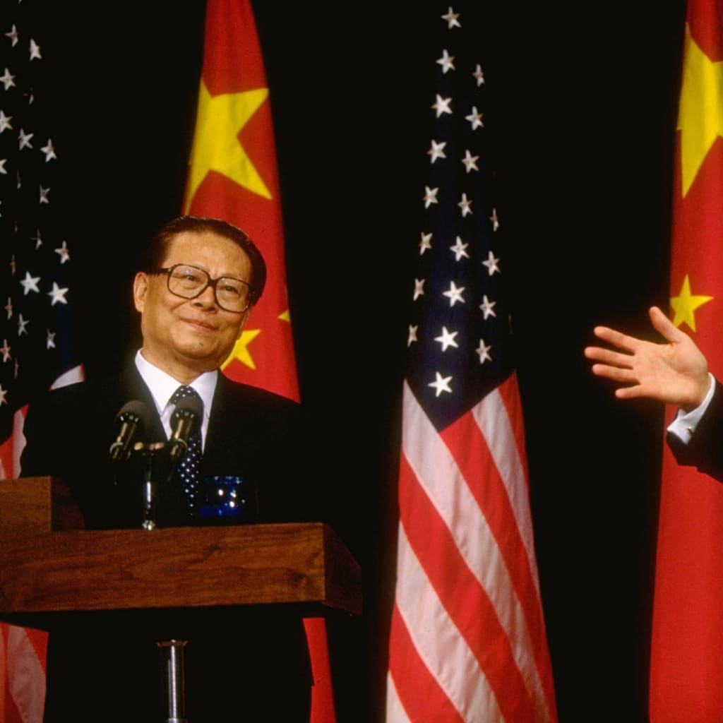 President Bill Clinton points to Chinese leader Jiang Zemin during joint press conference in front of U.S. and Chinese flags.
