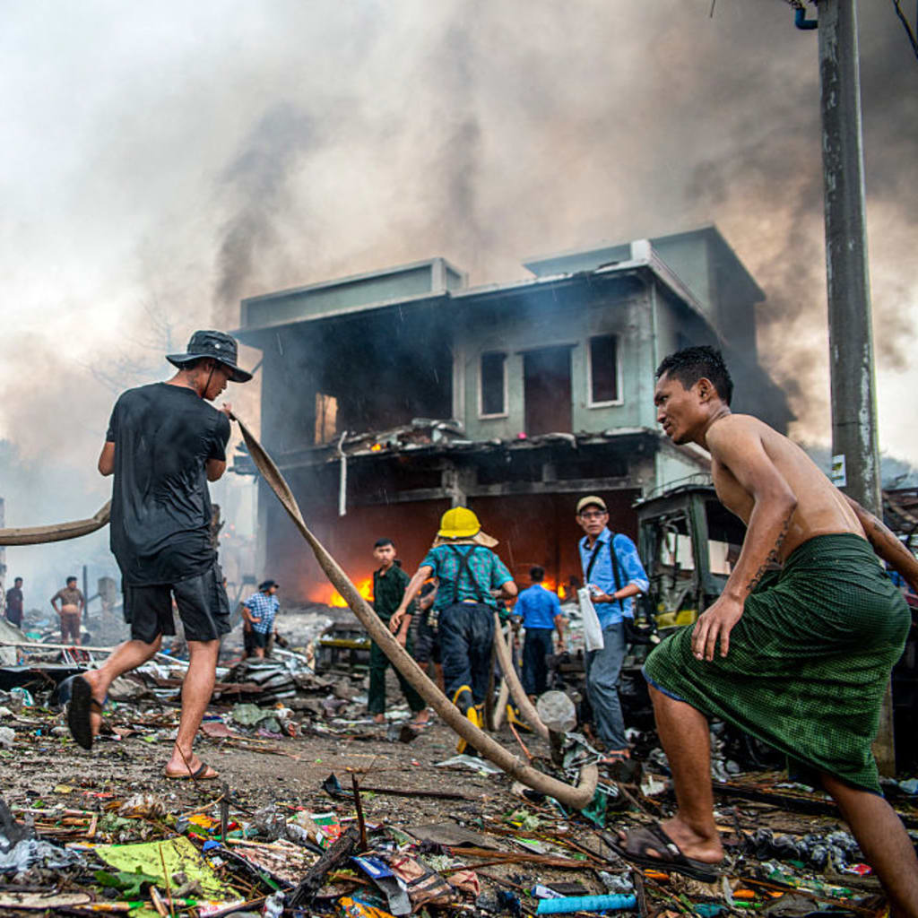 People extinguish a fire in a building that was destroyed in a bombardment carried out by Myanmar's military in Thabeikkyin Township in Mandalay Region of Central Myanmar on April 19, 2025.
