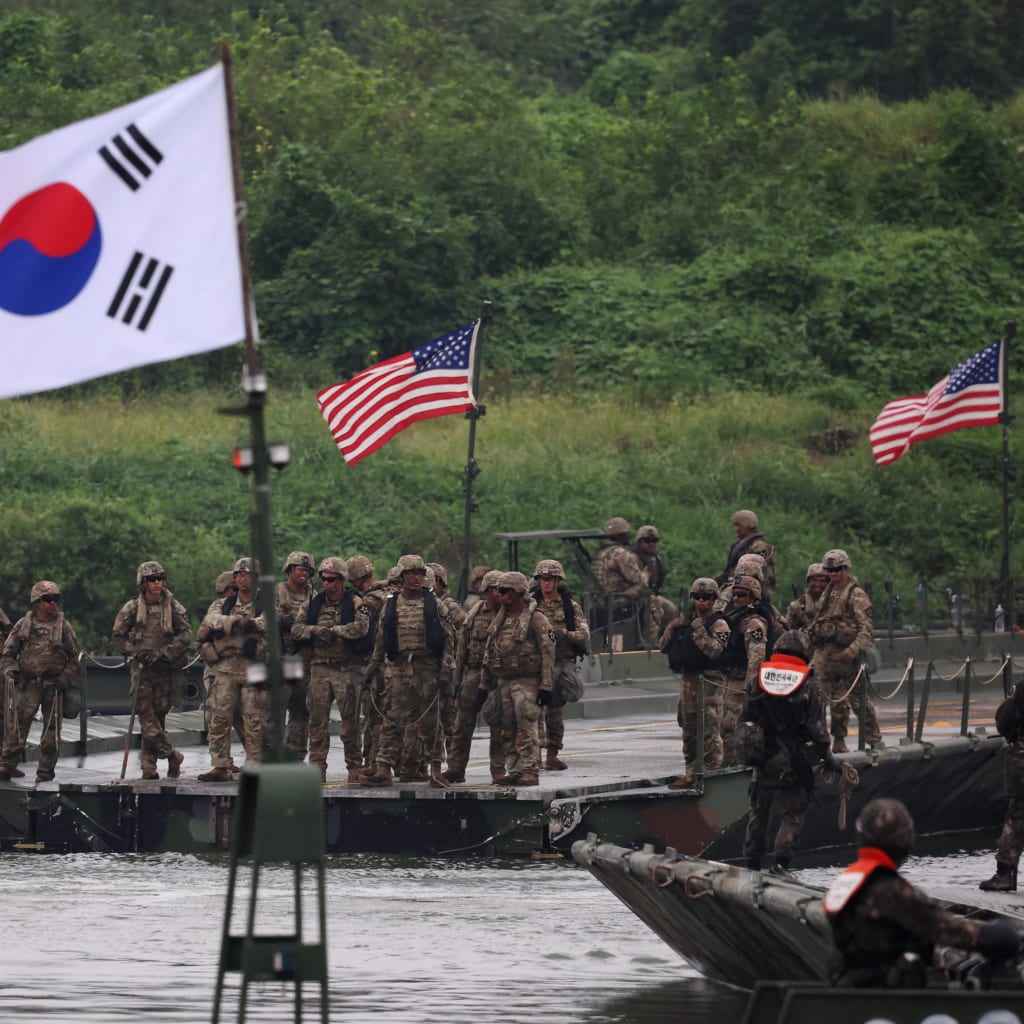 A South Korean flag flutters in the foreground as U.S. and South Korean army soldiers take part in a joint river-crossing exercise.
