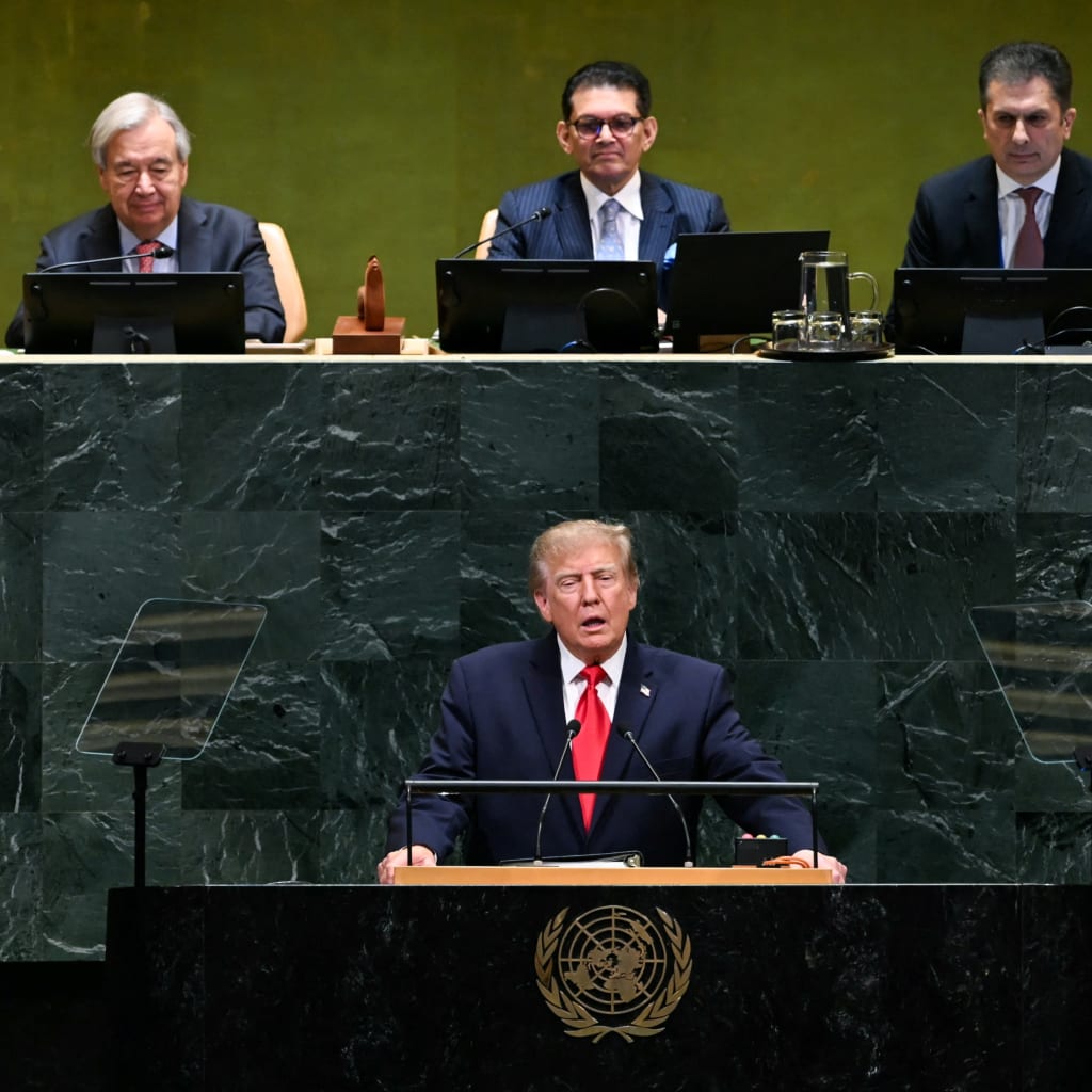 Trump stands at the green marble General Assembly rostrum, three UN officials seated at the dais above and behind him.