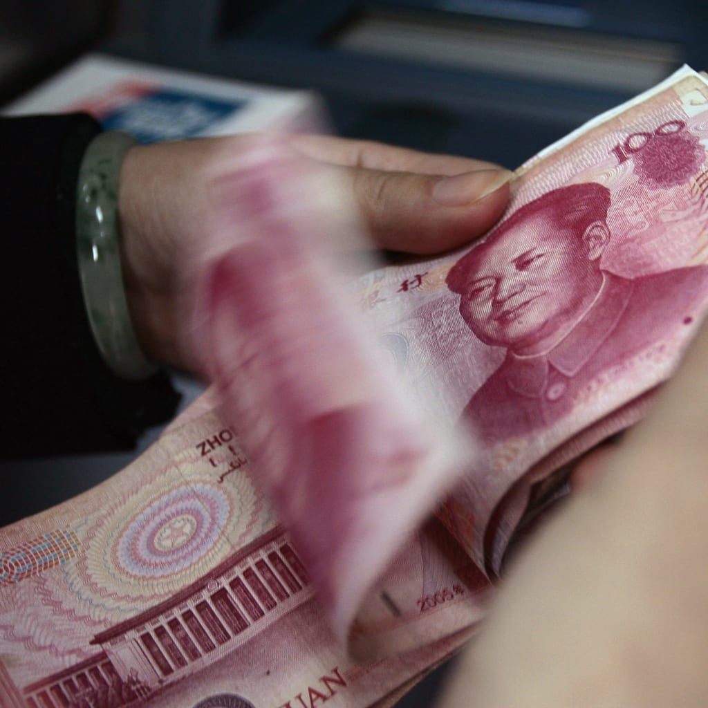 An employee counts Renminbi banknotes at a bank in Nanjing