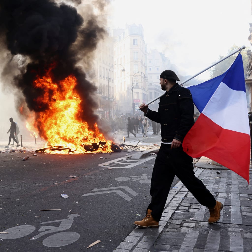 <p>A protester holds a French flag next to burning objects amid clashes in a street near the Place de Republique during a day of demonstrations in Paris, France, October 17, 2026. </p>
