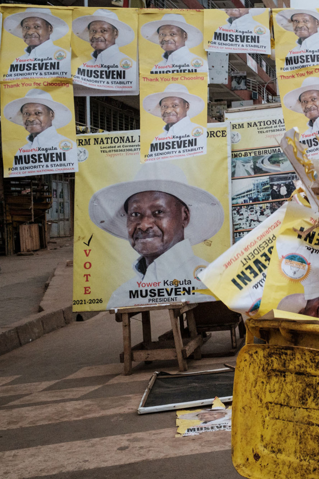 <p>A worker throws away campaign posters of Ugandan President Yoweri Museveni.</p>
