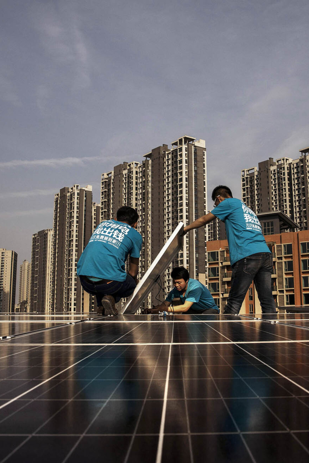<p>Workers install solar panels on a building’s roof in China.</p>
