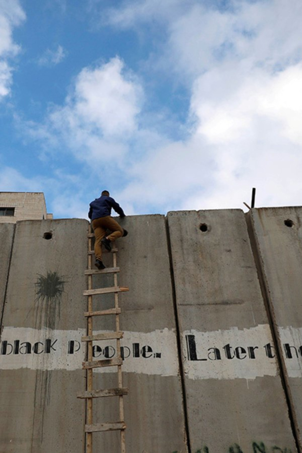 <p>A Palestinian climbs the Israeli barrier in the Israeli-occupied West Bank.</p>
