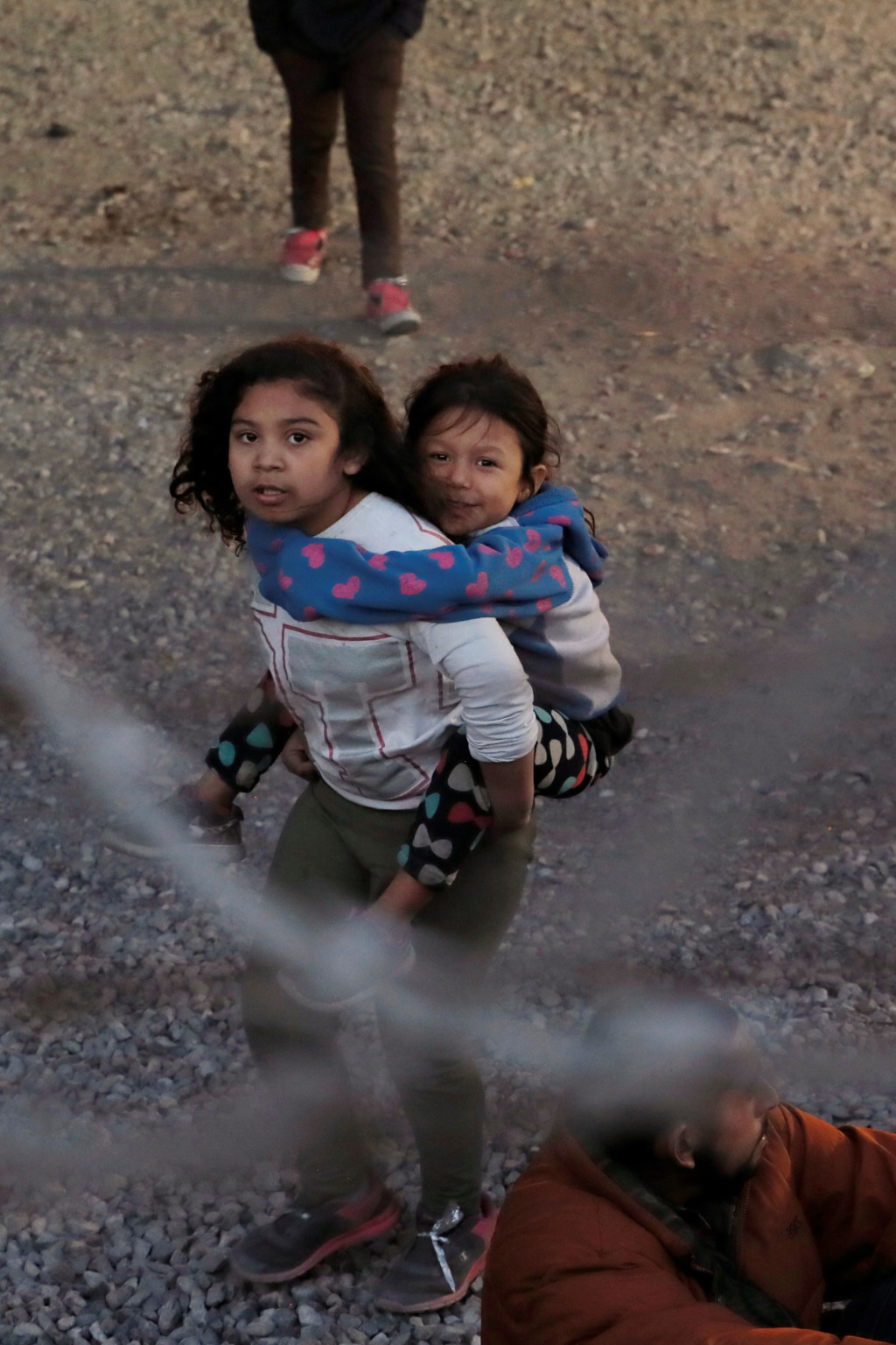 <p>A young girl carries a child inside a U.S. Customs and Border Protection holding area in El Paso, Texas.</p>
