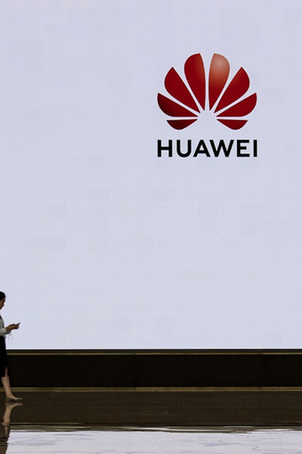 <p>A Huawei employee walks by a screen displaying the company’s logo at its Shenzhen headquarters.</p>
