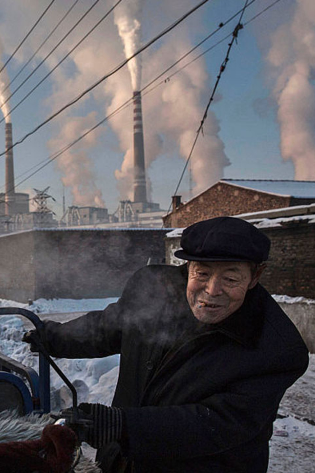 <p>Chinese men pull a tricycle in a neighborhood near to a coal power plant in Shanxi, China.</p>
