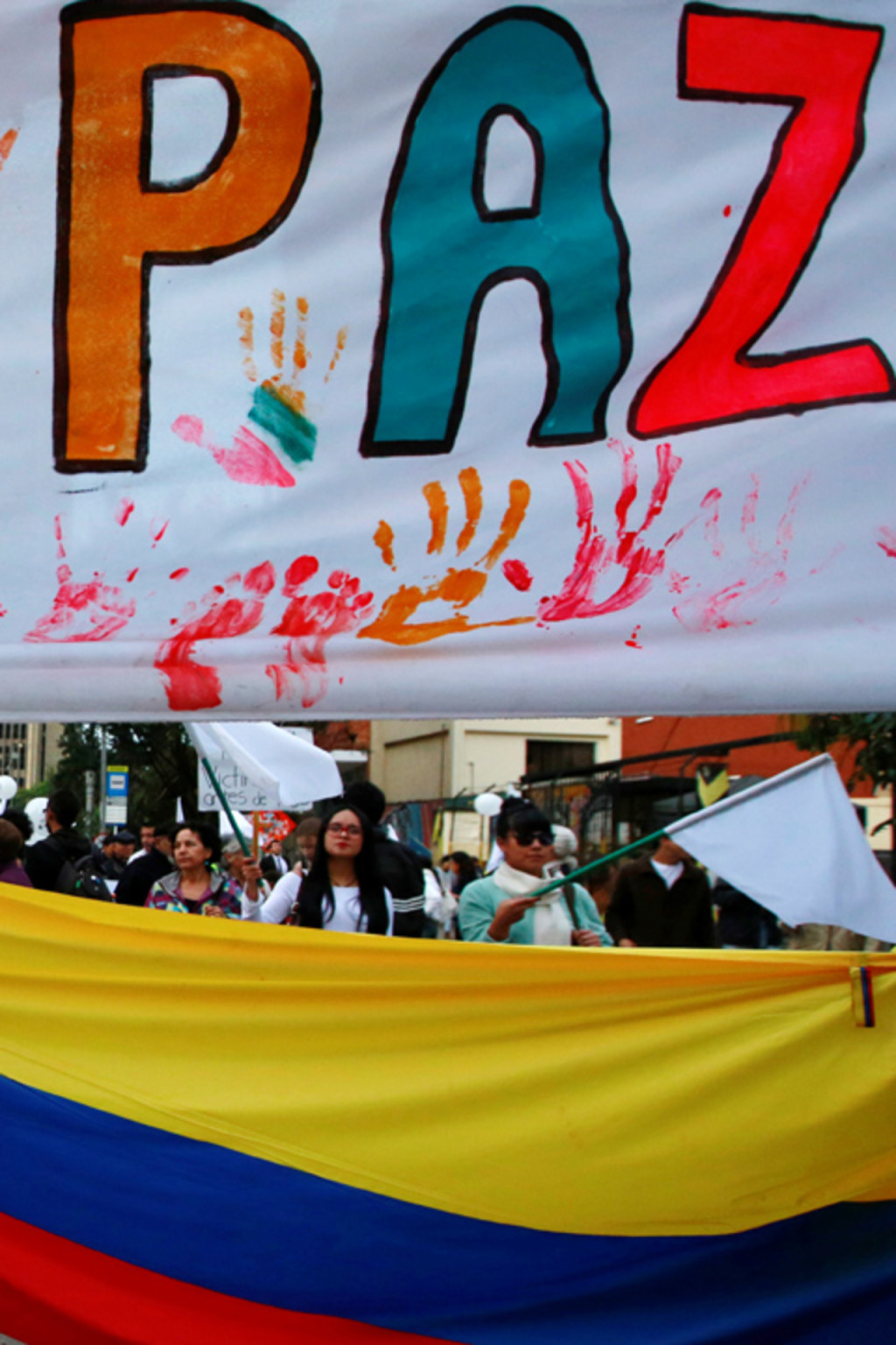 <p>A supporter rallying for a peace agreement between the Colombian government and FARC stands under a banner reading “for peace” during a march in Bogota.</p>
