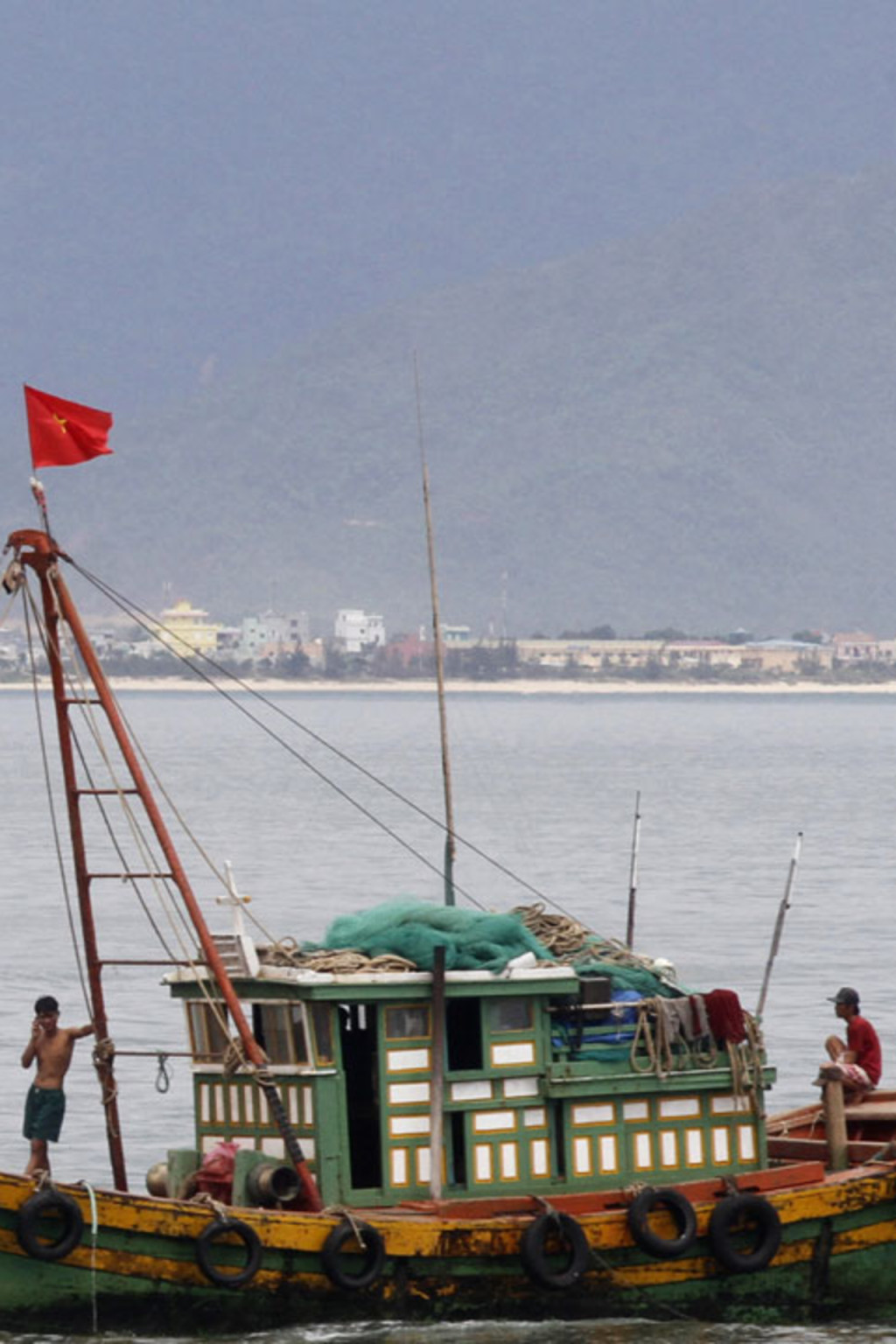 <p>A Vietnamese fishing boat goes past the USS Chung-Hoon at a port in Danang city, July 15, 2011.</p>
