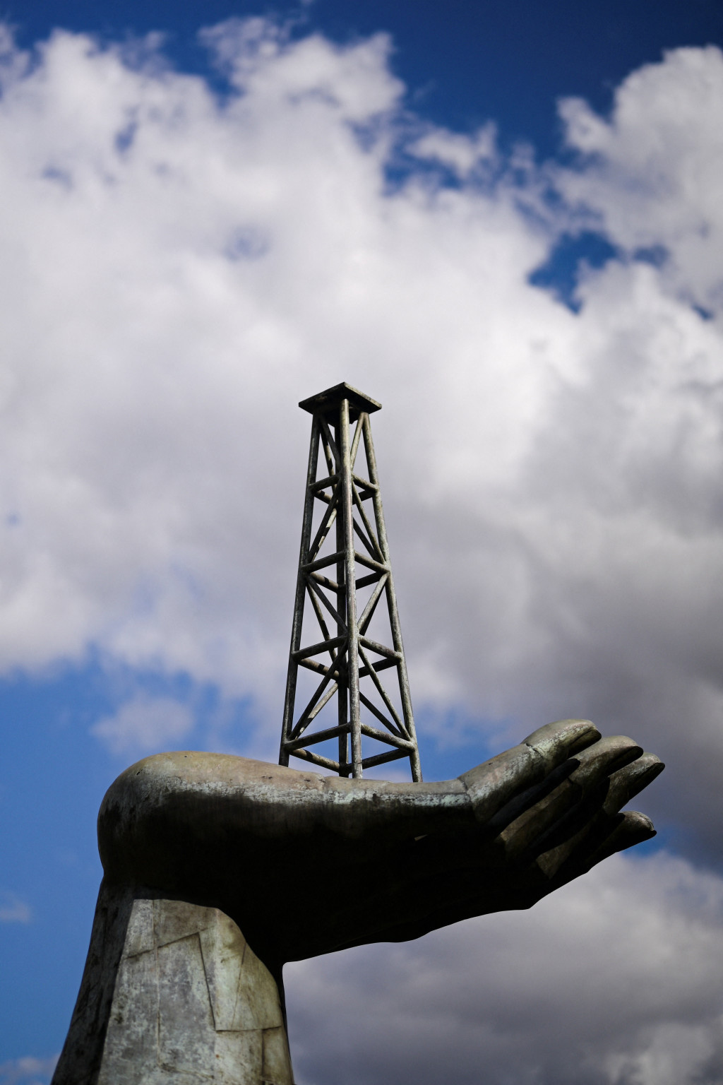 A structure of a hand holding an oil well tower stands near the headquarters of Venezuela's state-run oil company PDVSA, in Caraca