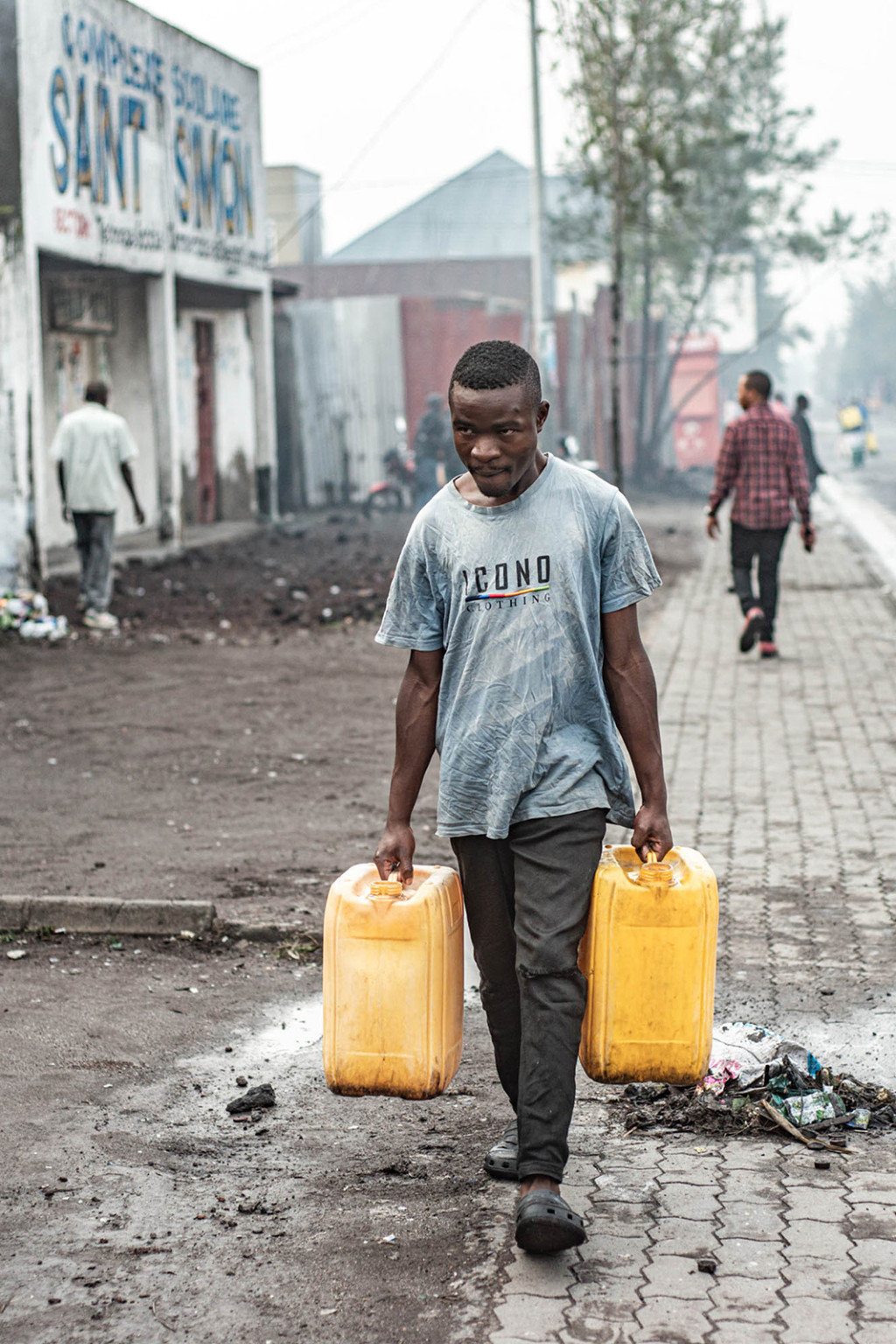 Man carries water jugs in DRC.