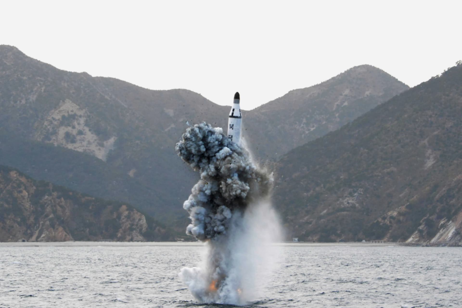 An underwater submarine ballistic missile is fired and emerges above the water with a large splash.