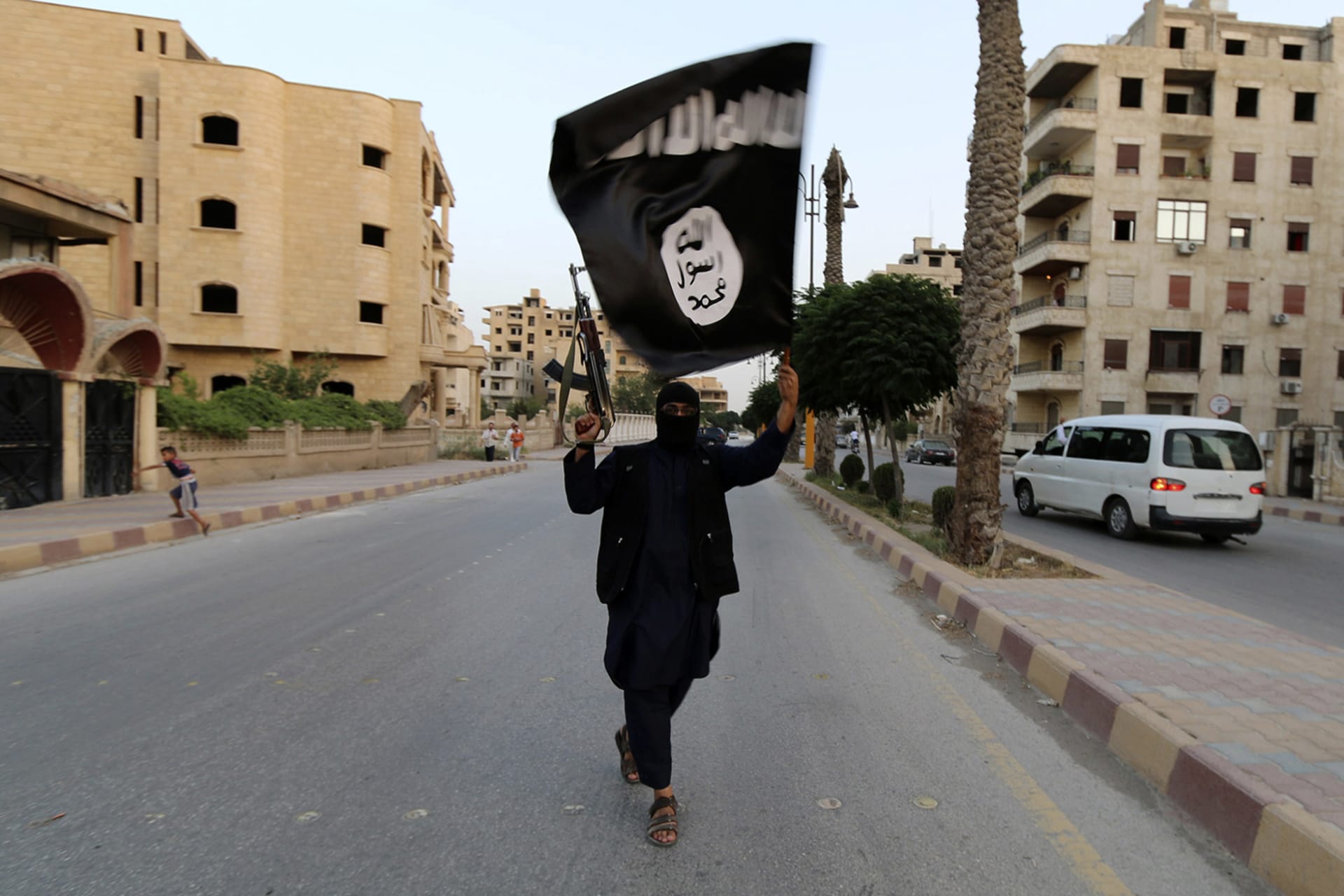A member loyal to the Islamic State waves an Islamic State flag in Raqqa on June 29, 2014.