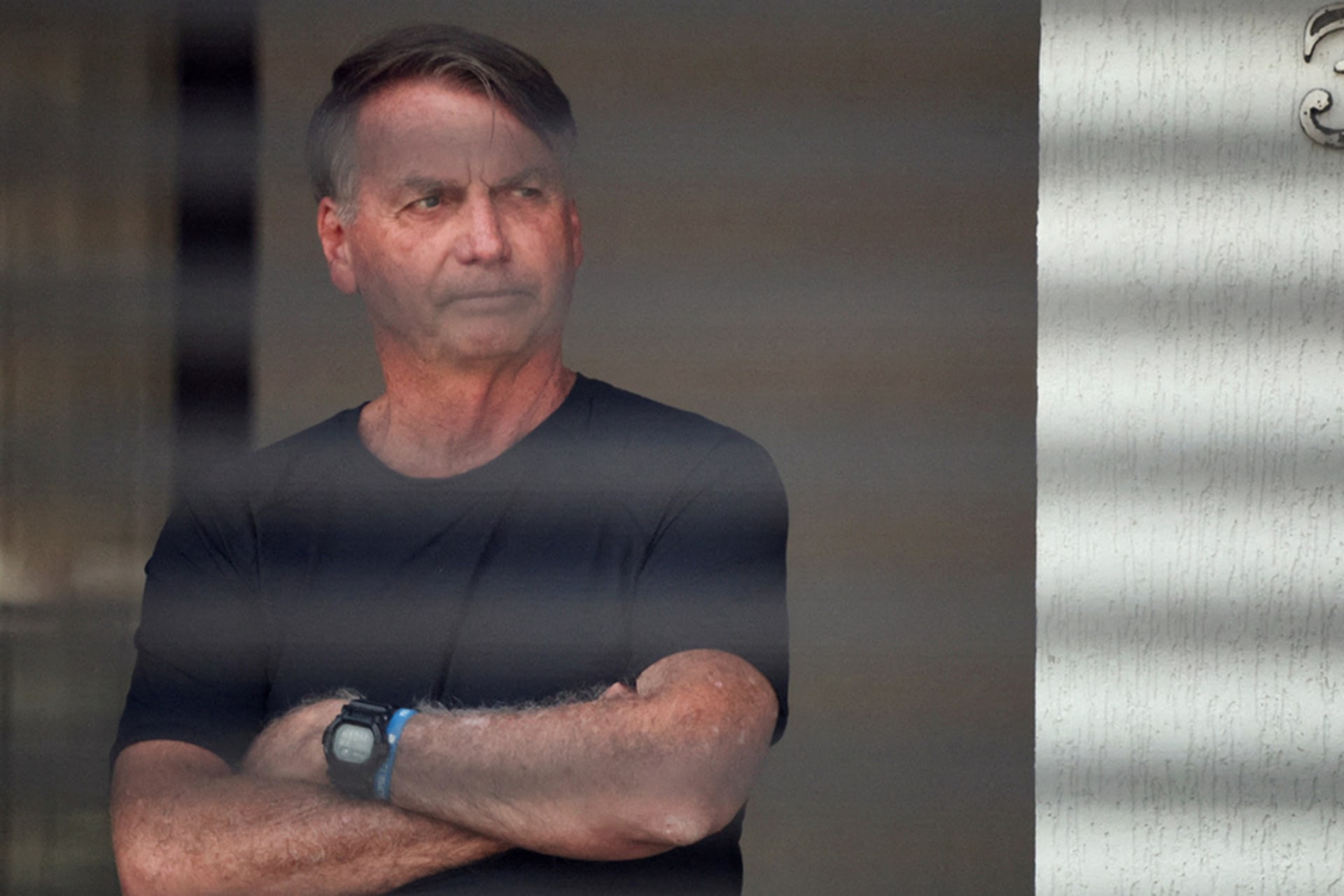 <p>Brazil’s former President Jair Bolsonaro stands at his home while under house arrest, ordered by Supreme Court Justice Alexandre de Moraes, as he awaits trial over an alleged plot to overturn the 2022 election, in Brasília, Brazil, August 14, 2025.</p>
