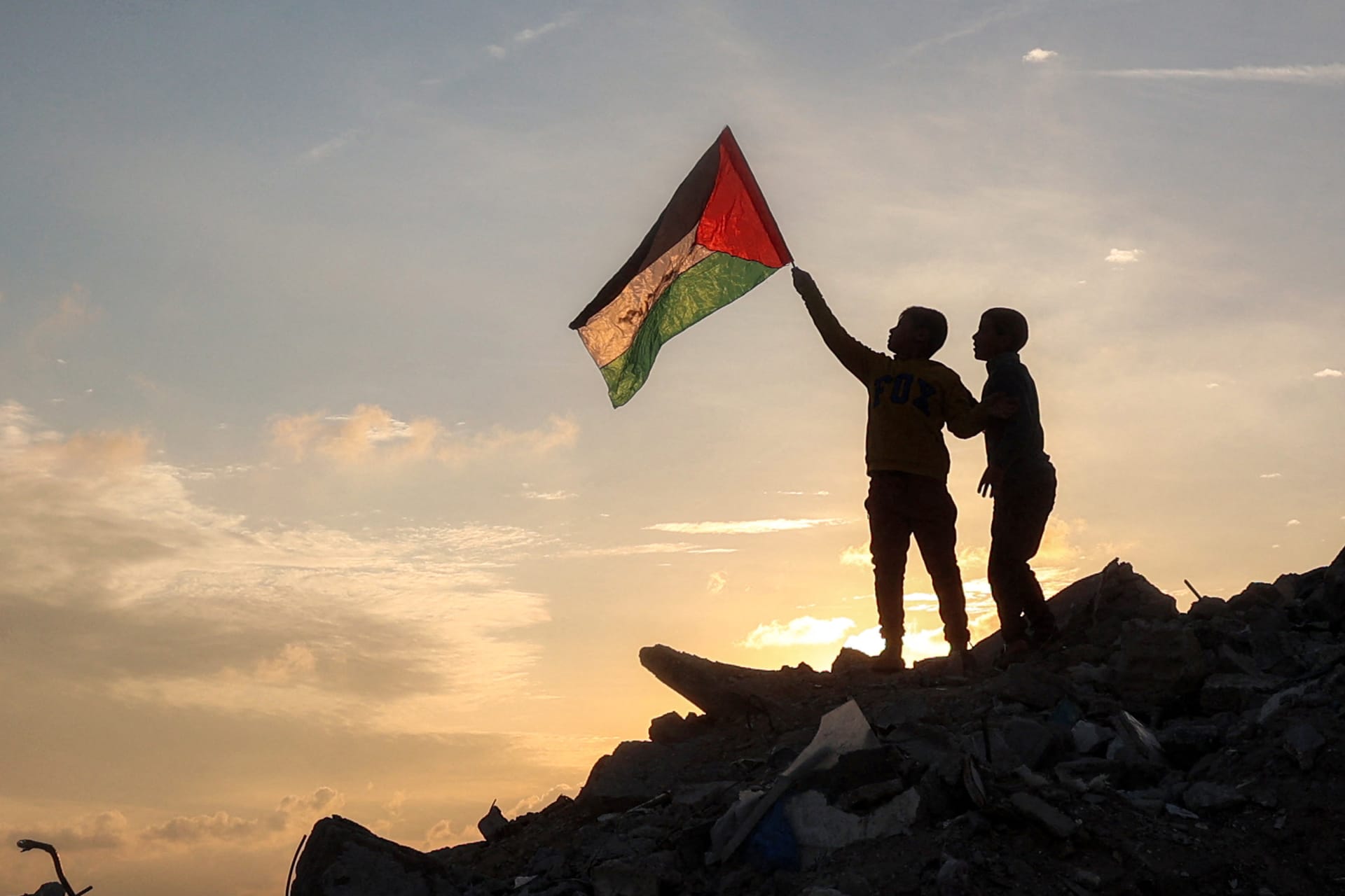 <p>A boy holds a Palestinian flag on top of a mound of rubble in the central Gaza Strip. </p>
