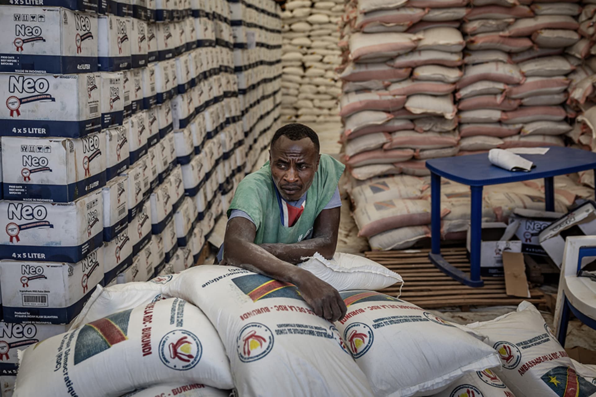 <p>A worker rests on top of sacks of aid stacked in a storage tent as Congolese refugees gather waiting for a chance to receive food assistance in Giharo, Democratic Republic of Congo.</p>
