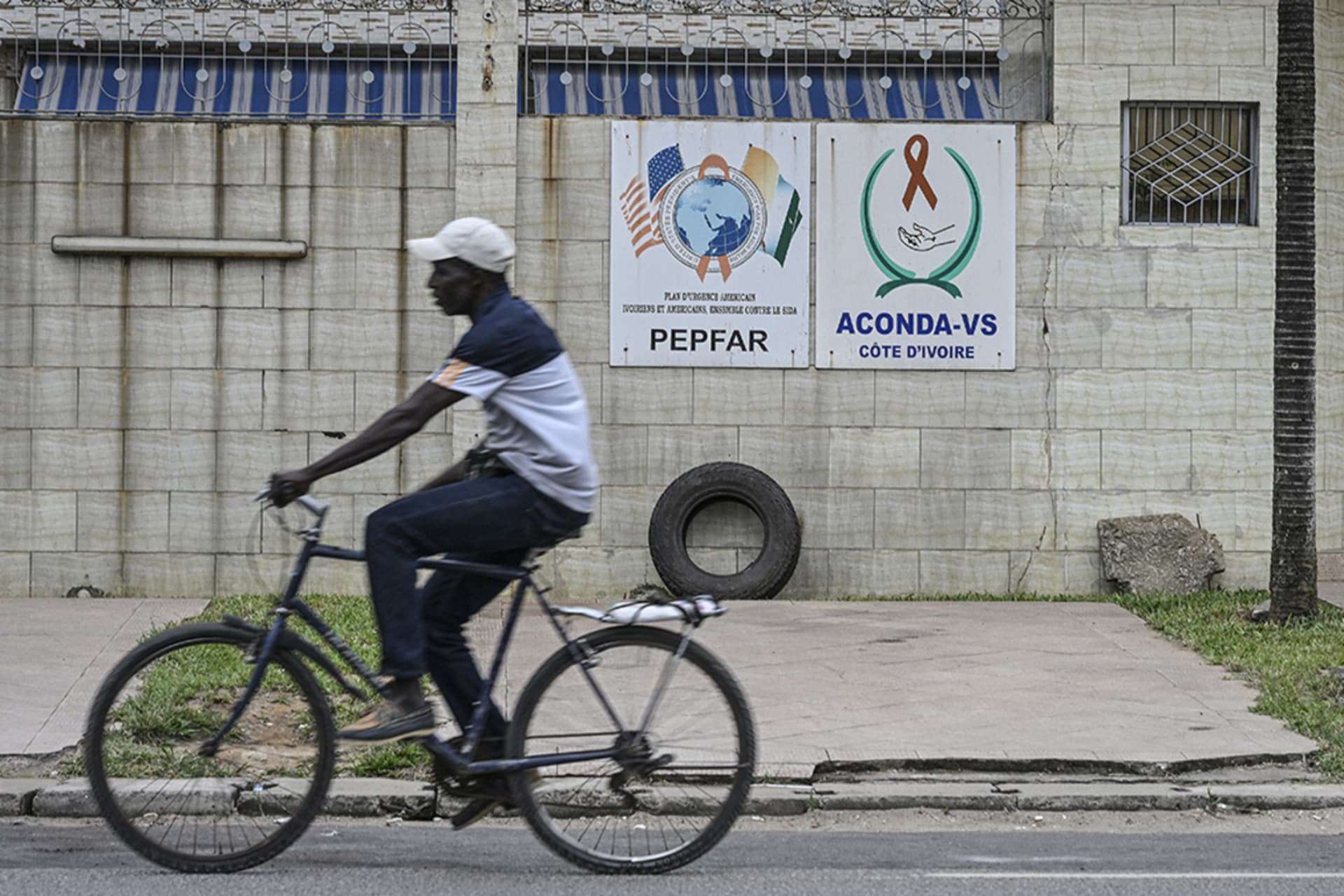<p>A man rides past a PEPFAR sign in the city of Abidjan, Ivory Coast, July 12, 2025.</p>

