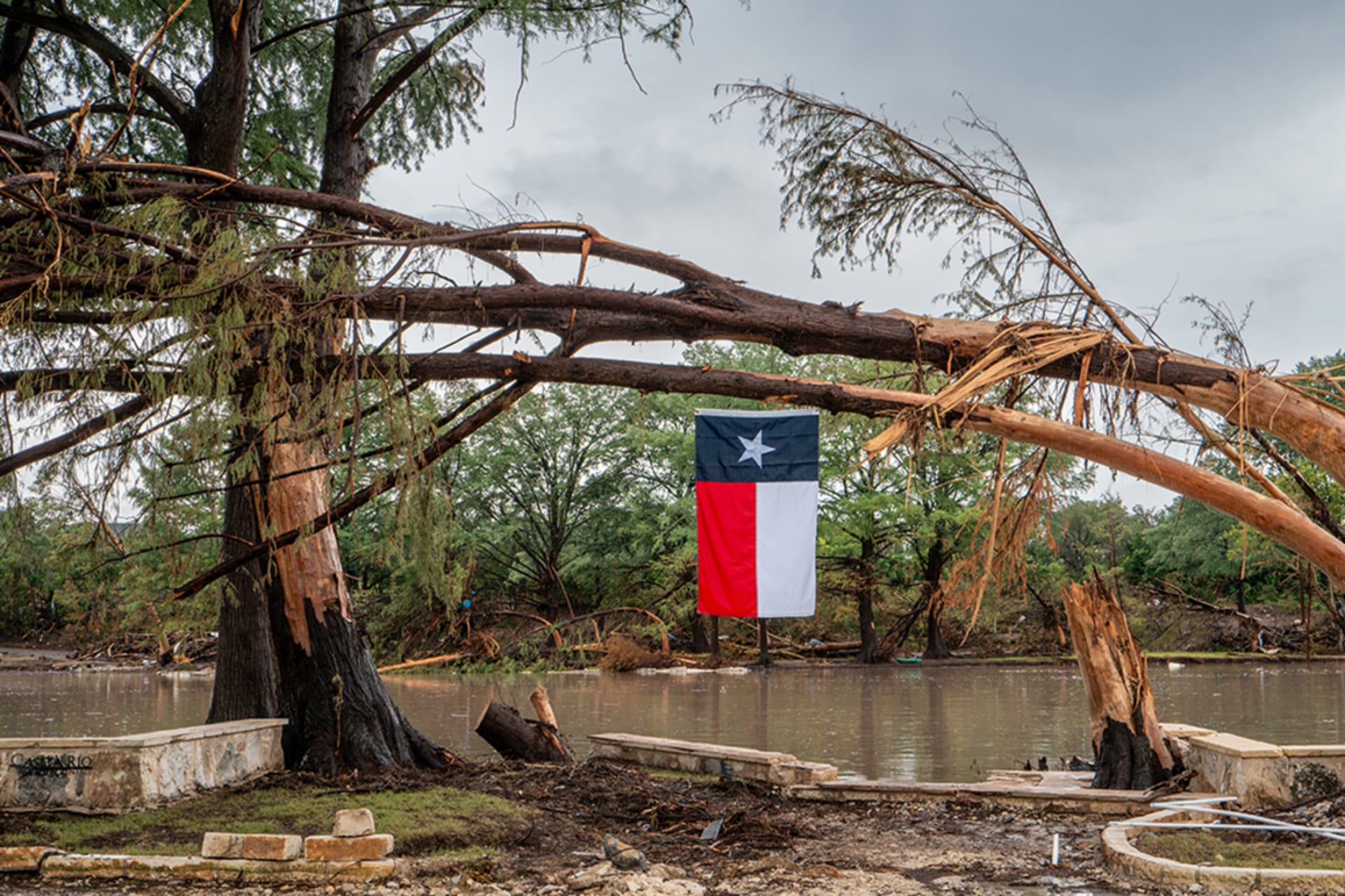<p>A Texas flag hangs from a storm-damaged tree on the banks of the Guadalupe River in Center Point, Texas, July 13, 2025.</p>
