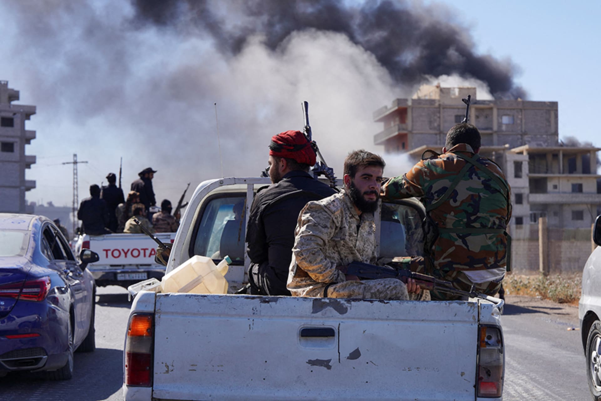 <p>Smoke rises while Syrian security forces sit in the back of a truck as Syrian troops entered the predominantly Druze city of Sweida on Tuesday following two days of clashes, July 15, 2025.</p>
