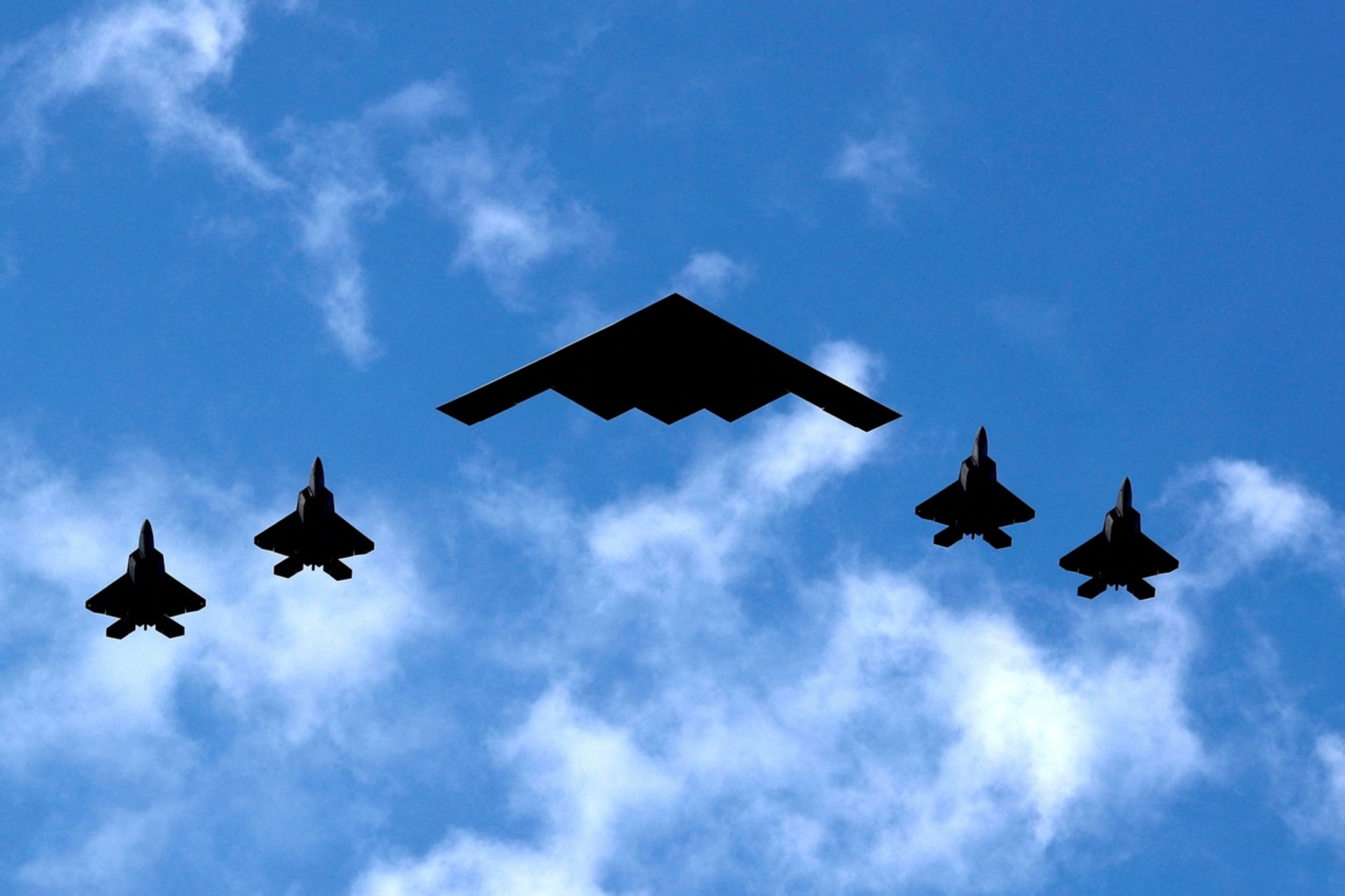 <p>A U.S. Air Force B-2 Bomber is flanked by four F-22 Raptor fighter planes during a flyover down the Hudson River and past New York City on July 4, 2020.</p>
