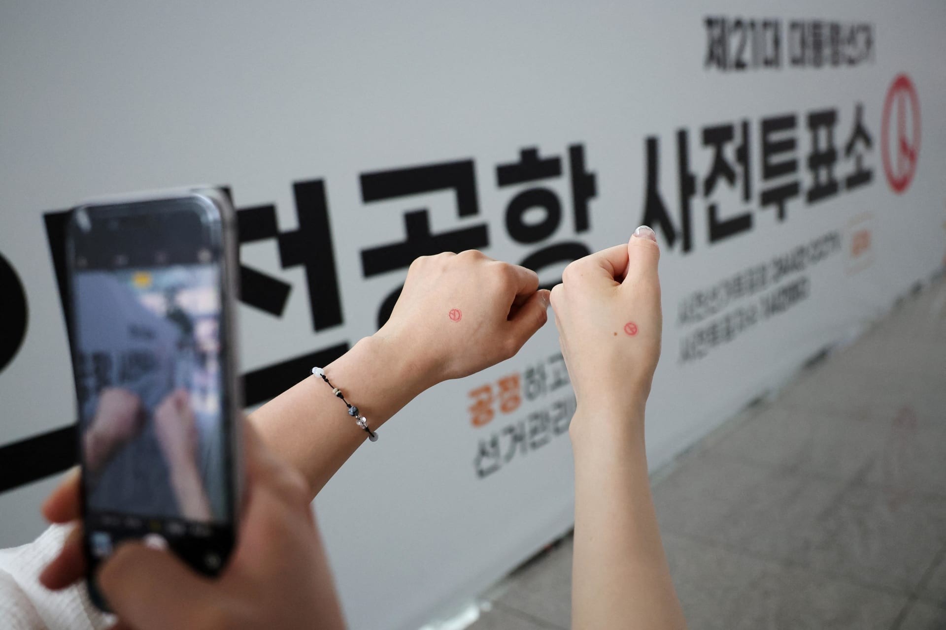 <p>Women take souvenir photos after casting their early vote for the upcoming presidential election at a polling station at the Incheon International airport in Incheon, South Korea, May 29, 2025.</p>
