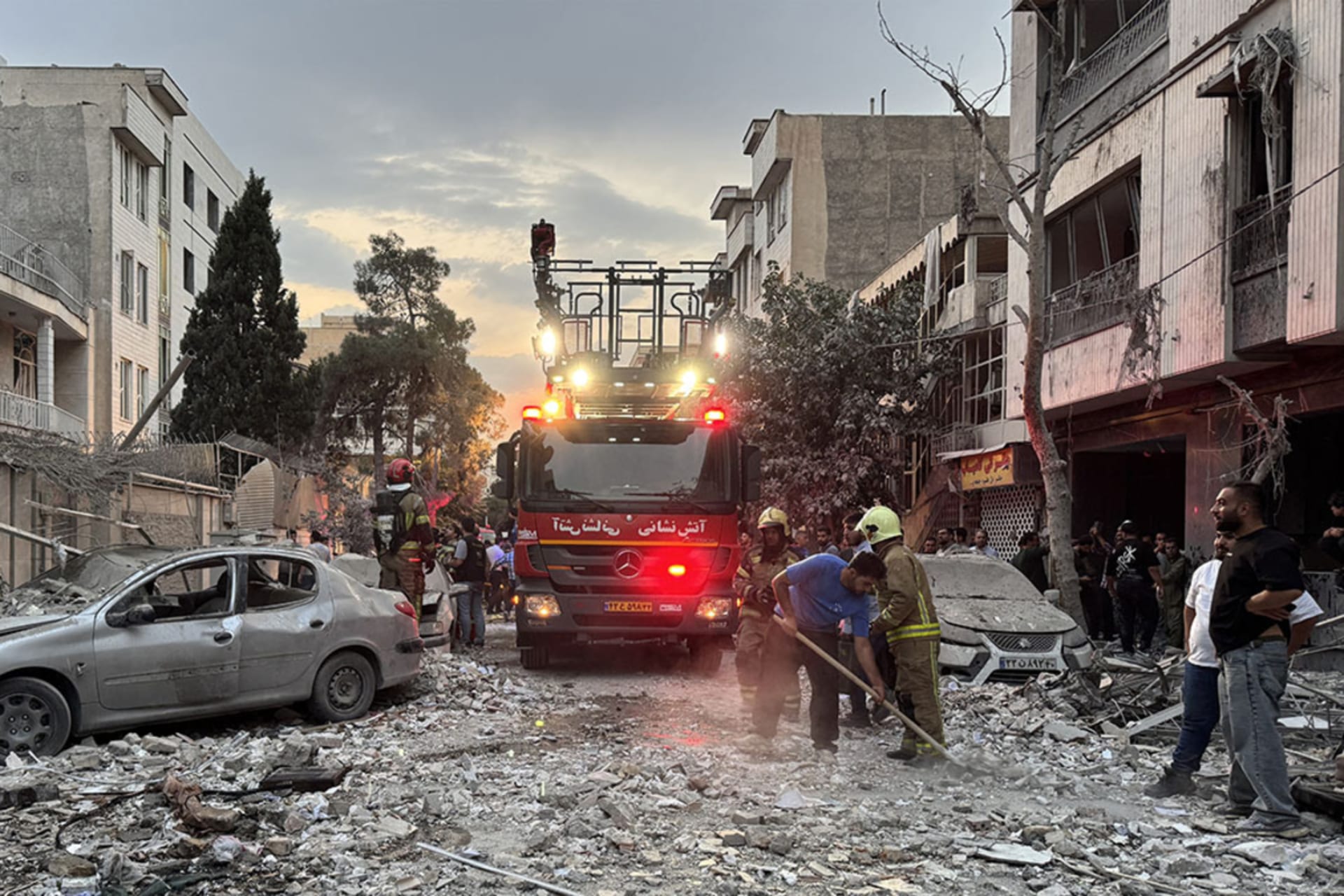 <p>First responders gather outside a building in Tehran that was hit by an Israeli strike on June 13, 2025.</p>
