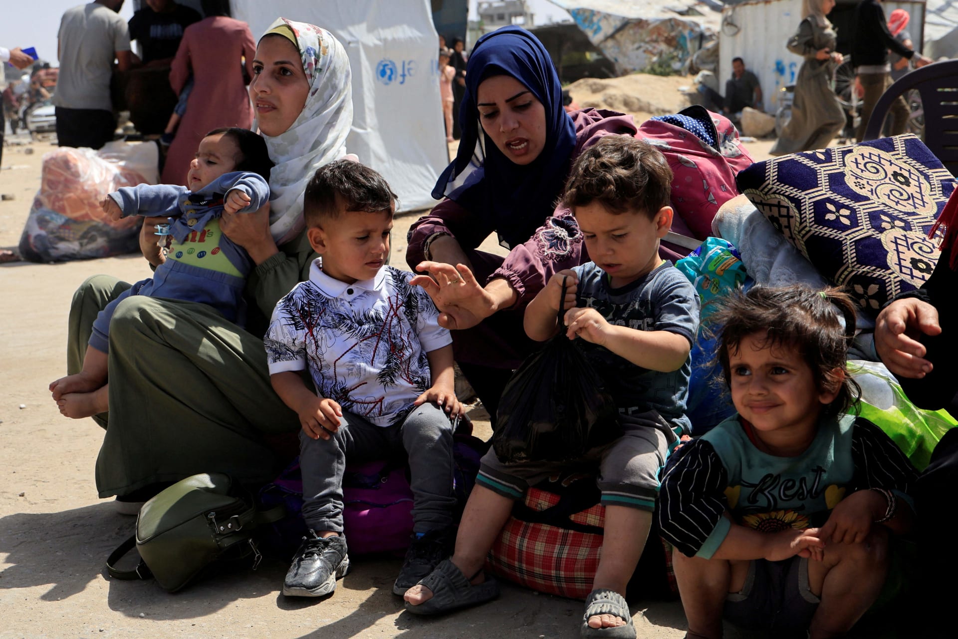 <p>Palestinian women and children rest with their belongings as they flee their homes after the Israeli military issued orders for evacuation from eastern Khan Younis, in the southern Gaza Strip, May 19, 2025. </p>
