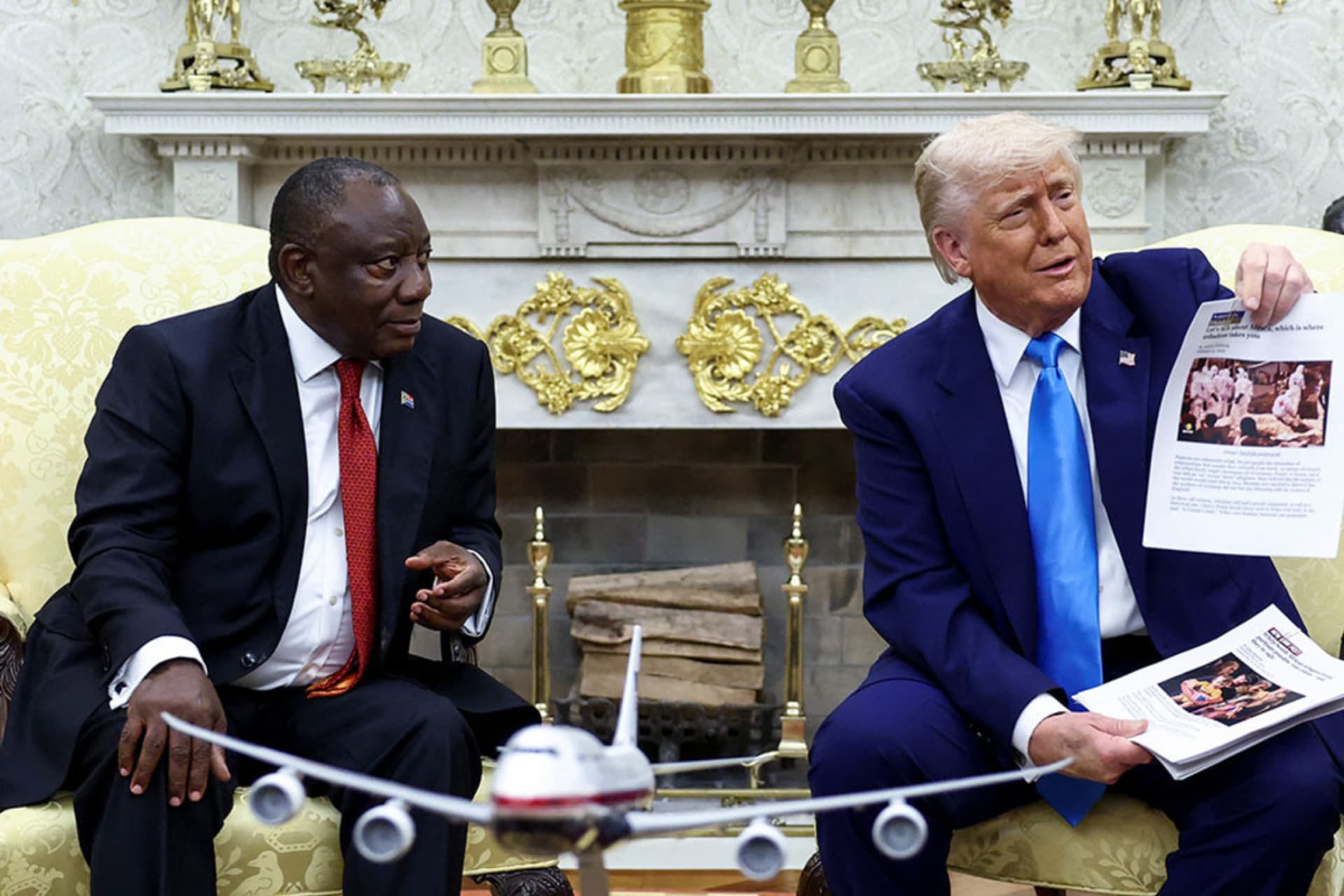 <p>U.S. President Donald Trump holds up printed papers showing alleged news reports of violence as he meets South African President Cyril Ramaphosa in the Oval Office.</p>
