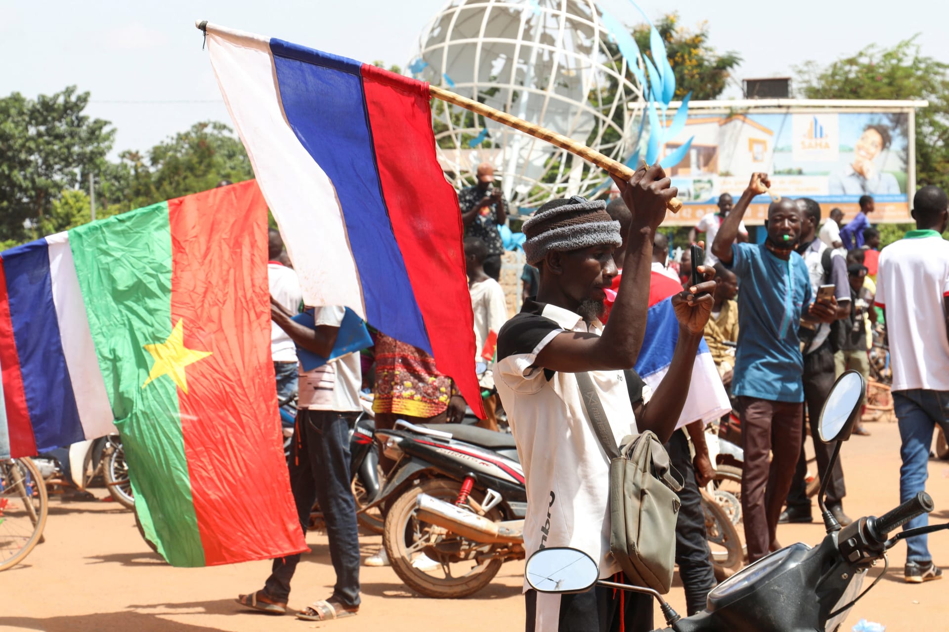 <p>Supporters of Burkina Faso’s junta hold Burkinabè and Russian flags as they gather to protest against the arrival of an ECOWAS (Economic Community of West African States) delegation in Ouagadougou, Burkina Faso, on October 4, 2022.</p>
