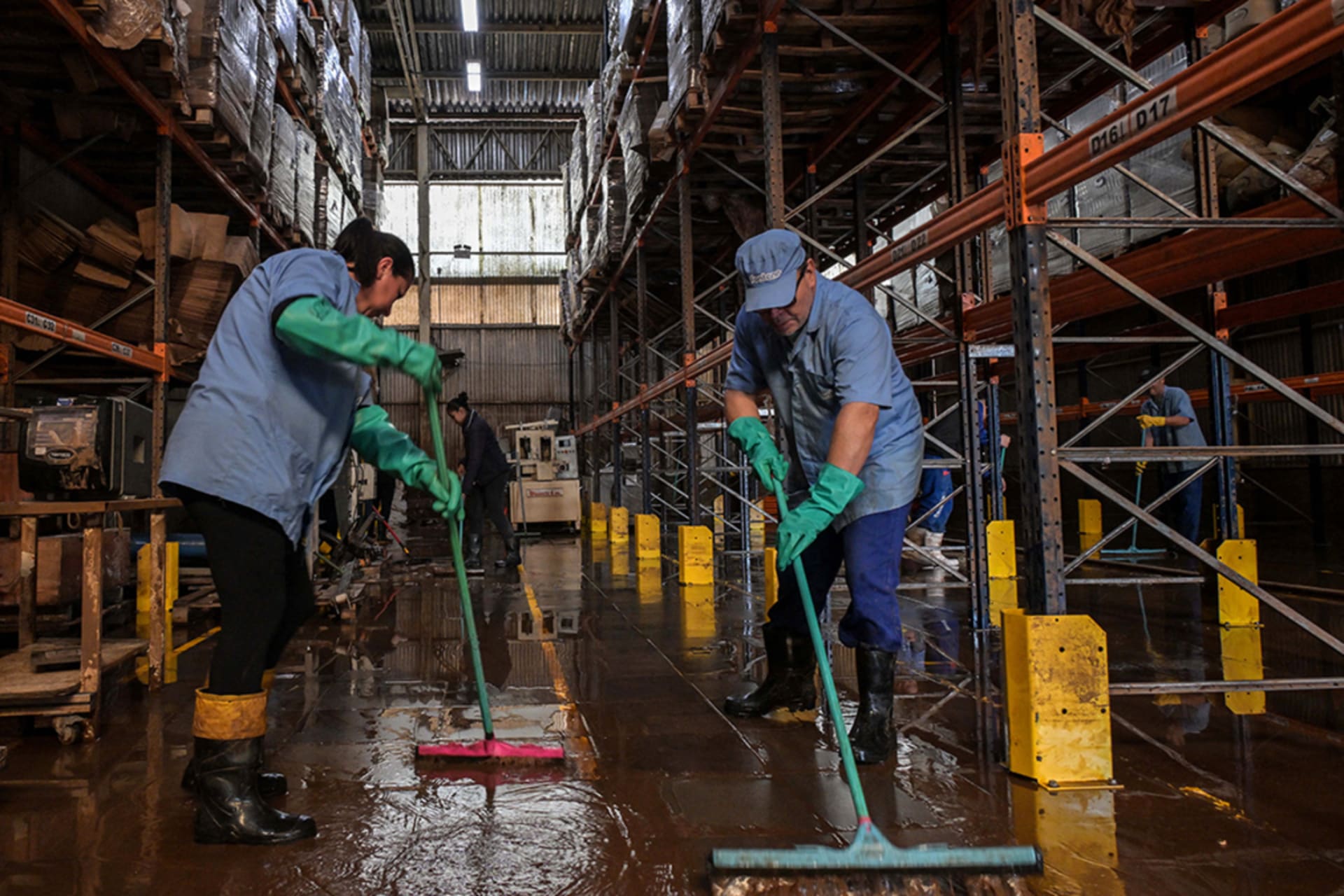 <p>Workers remove mud accumulated by flooding at an industrial plant in Rio Grande do Sul, Brazil.</p>
