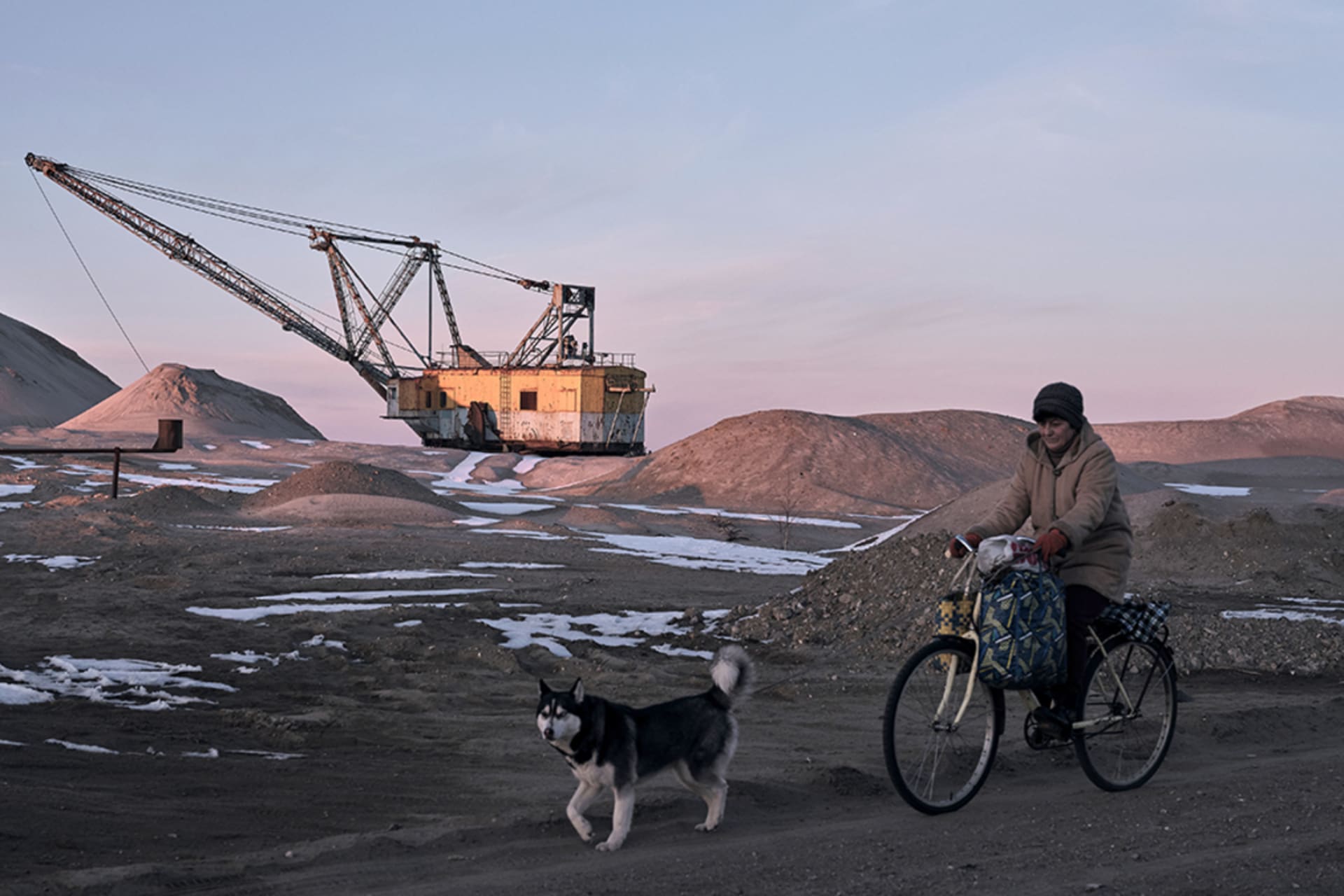 <p>A woman cycles past with her dog as Drag-line excavator mines rare earth materials in Ukraine on February 25, 2025.</p>
