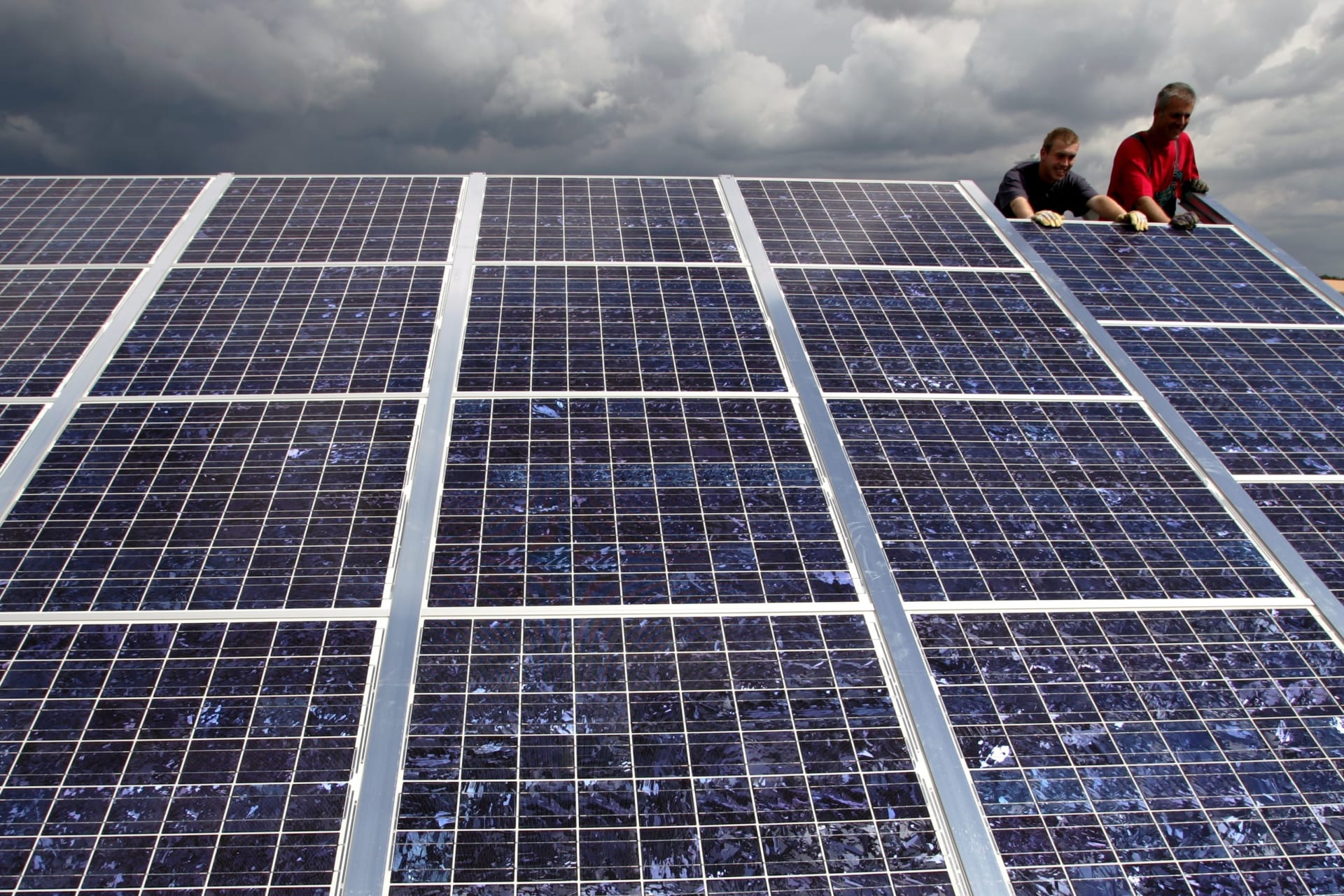 <p>Workers set up solar panels in a solar park in Goettelborn, Germany.</p>
