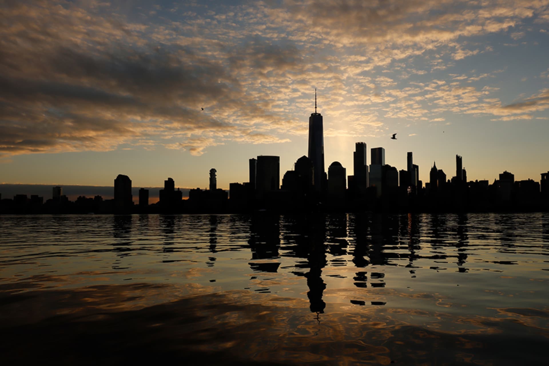 <p> The skyline of New York City’s lower Manhattan is reflected in the Hudson River. New York City is one of several American cities that will face severe flooding this century. </p>
