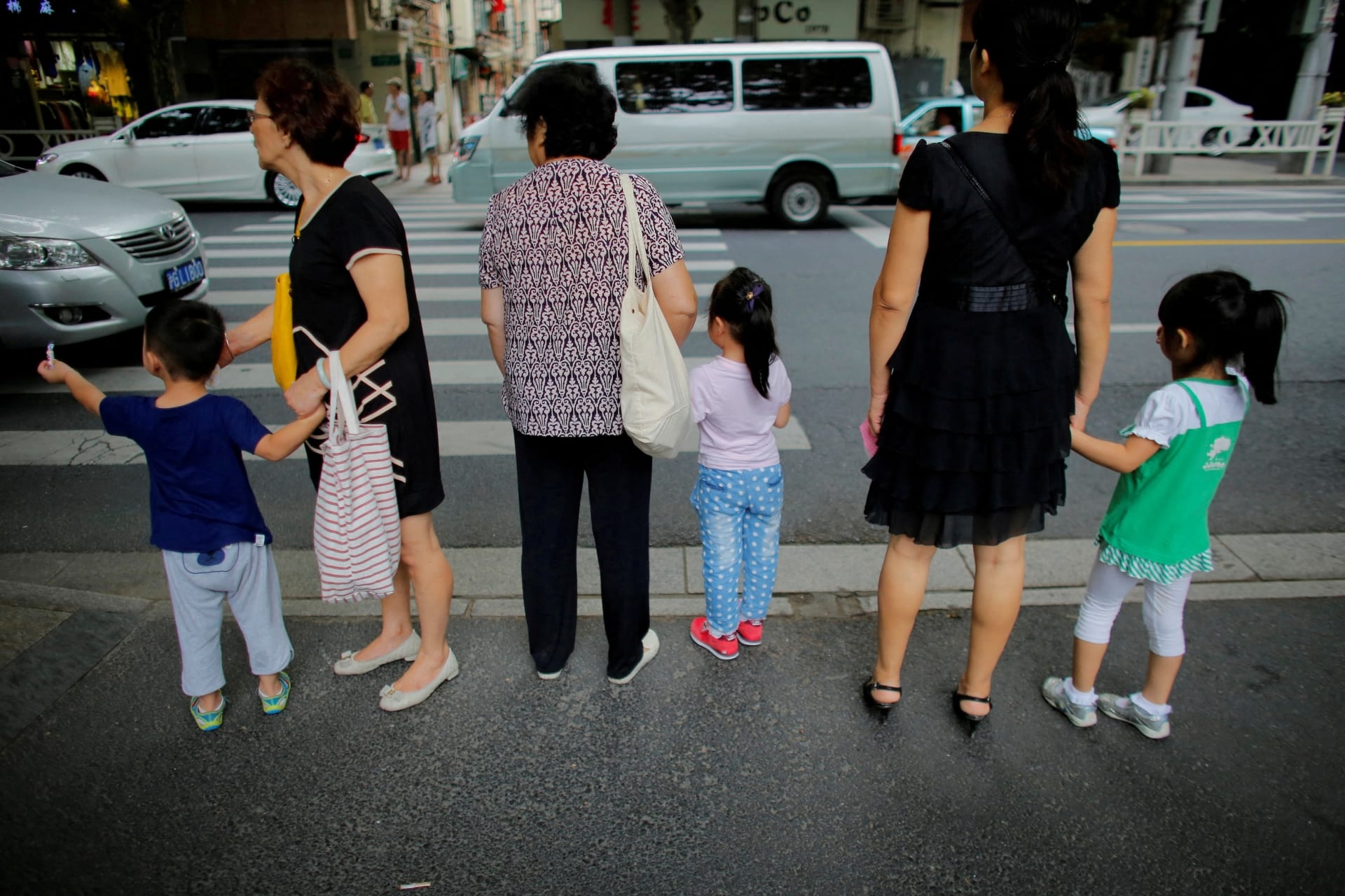 <p>Women hold childrens’ hands as they wait to cross a street after school in downtown Shanghai, China September 12, 2014.</p>
