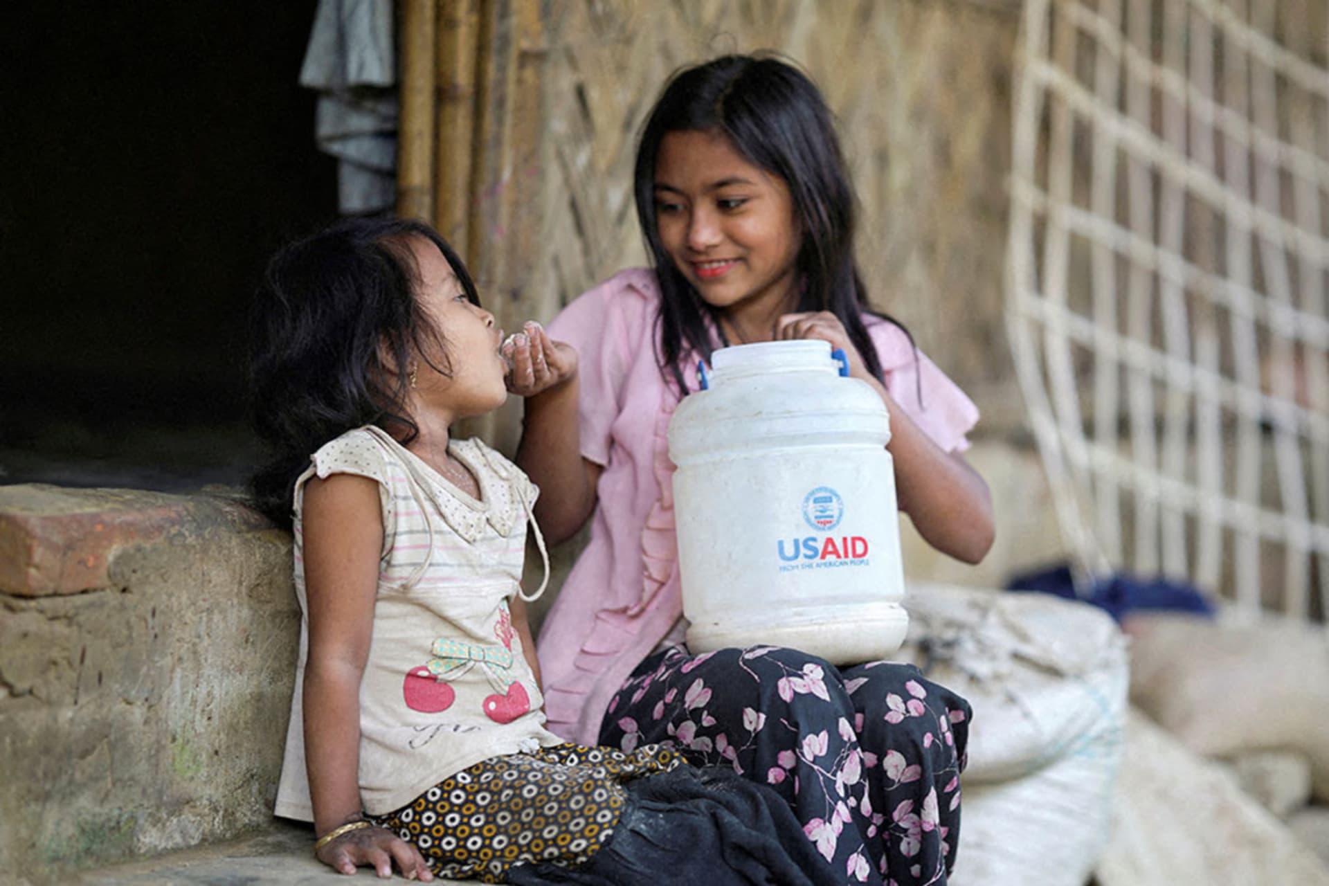 <p>A Rohingya girl feeds a child from a jar with the USAID logo on it, at a refugee camp in Cox’s Bazar, Bangladesh, February 11, 2025. </p>

