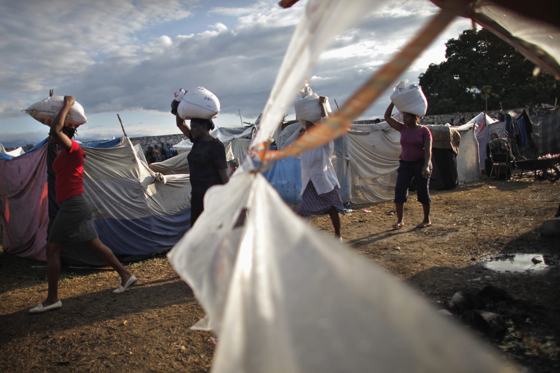 <p>Women carry bags of rice from USAID as part of food distributed by various relief agencies in Cite Soleil, Port-au-Prince February 18, 2010.</p>
