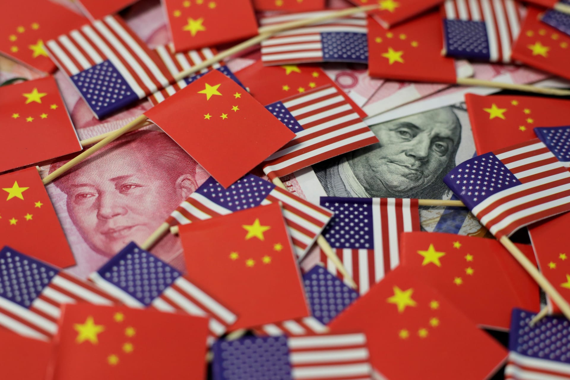 <p>A U.S. dollar banknote featuring American founding father Benjamin Franklin and a China’s yuan banknote featuring late Chinese chairman Mao Zedong are seen among U.S. and Chinese flags in this illustration picture taken May 20, 2019.</p>
