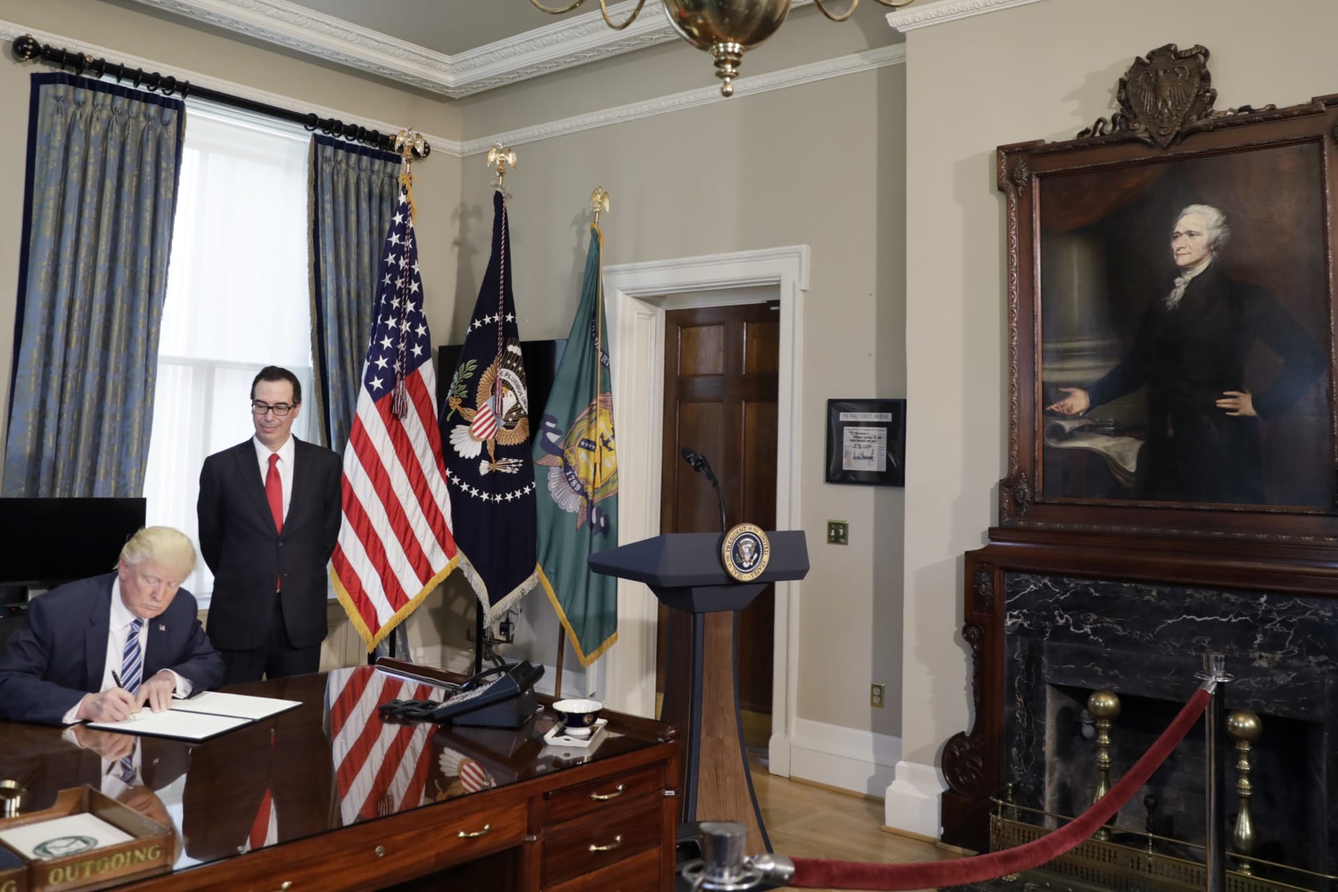 <p>With a portrait of the first U.S. Treasury Secretary Alexander Hamilton looking on, U.S. President Donald Trump (L) signs a financial services executive order as Treasury Secretary Steven Mnuchin stands by at the Treasury Department in Washington, U.S.</p>
